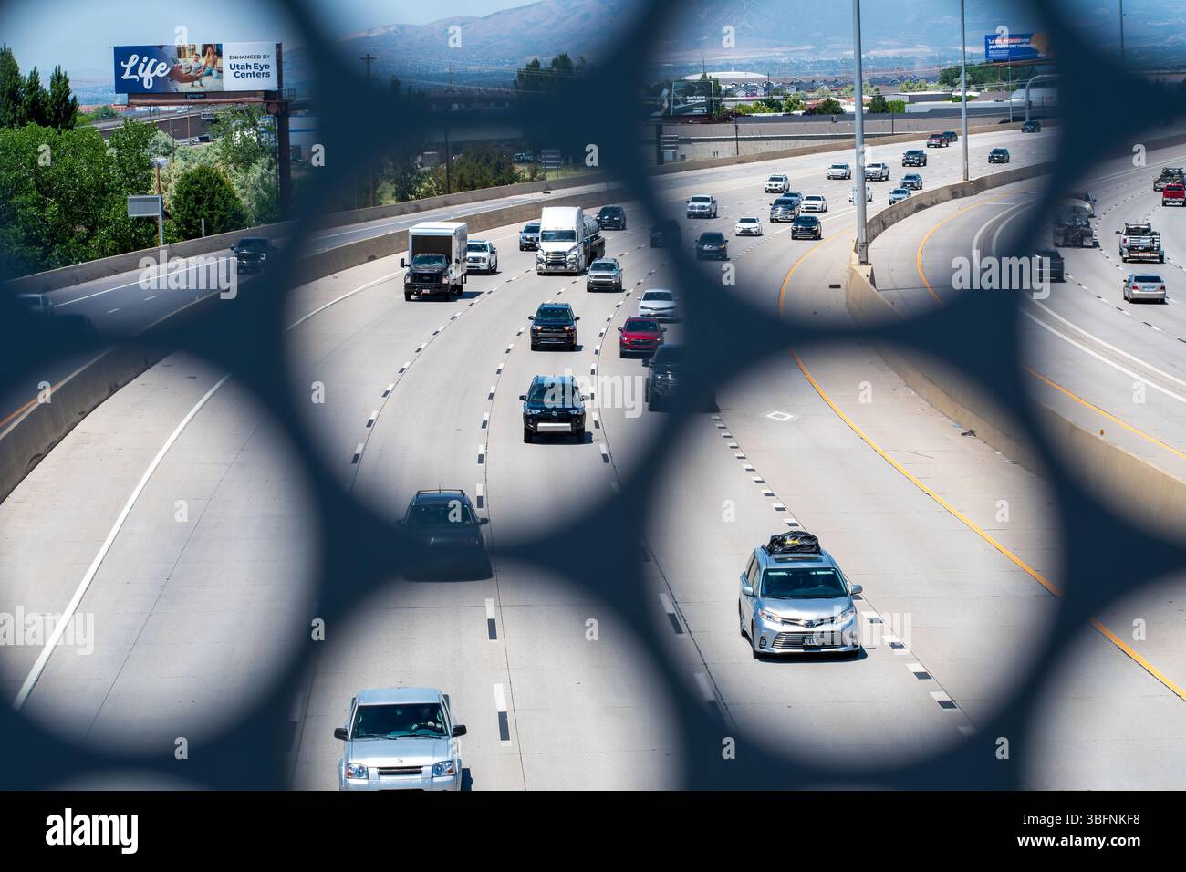 Orem, Utah – 2 juin 2025 : la circulation en direction du nord se déplace le long de l'Interstate 15 comme vu à travers une ouverture structurelle dans le pont piétonnier UVU à Orem, UT. Banque D'Images