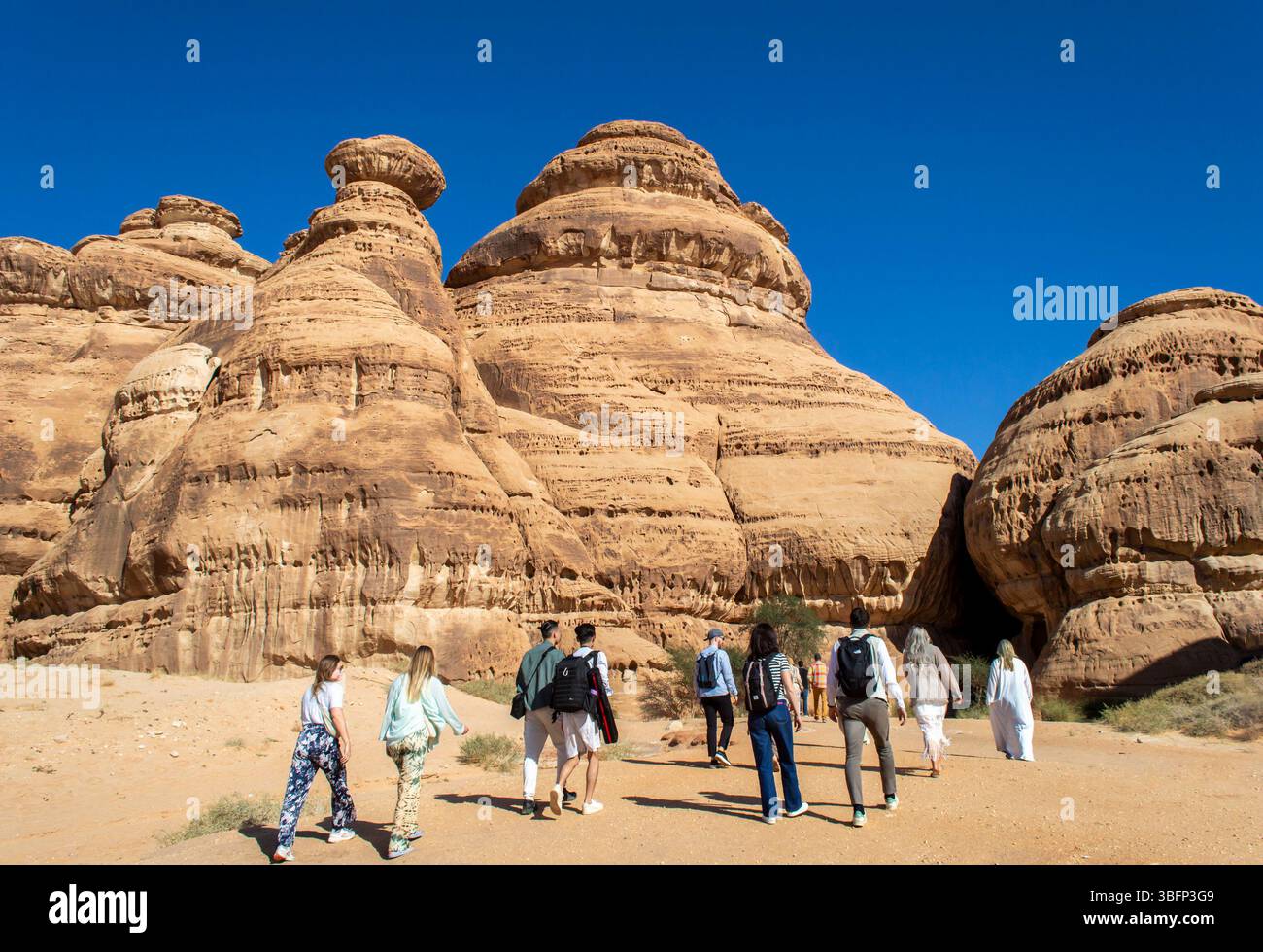 Alula, Arabie Saoudite, 4 avril 2024. Vue arrière d'un groupe de touristes marchant vers la montagne rocheuse à Jabal Ithlib, Hegra dans une journée ensoleillée. Banque D'Images Alula, Arabie Saoudite, 4 avril 2024. Vue arrière d'un groupe de touristes marchant vers la montagne rocheuse à Jabal Ithlib, Hegra dans une journée ensoleillée. Banque D'Images
