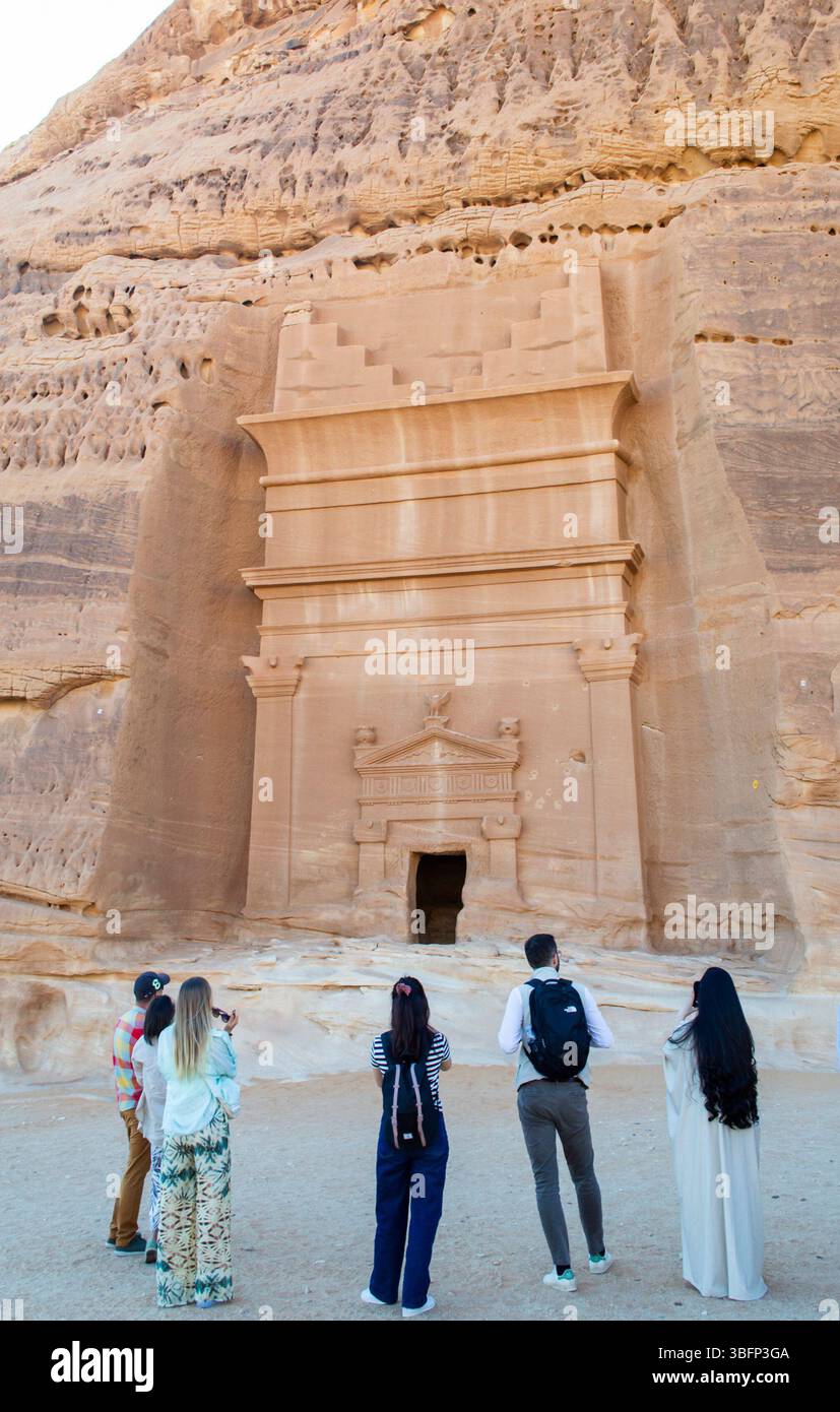 Alula, Arabie Saoudite, 4 avril 2024. Vue arrière d'un petit groupe de touristes debout devant la tombe rocheuse à Hegra. Banque D'Images Alula, Arabie Saoudite, 4 avril 2024. Vue arrière d'un petit groupe de touristes debout devant la tombe rocheuse à Hegra. Banque D'Images