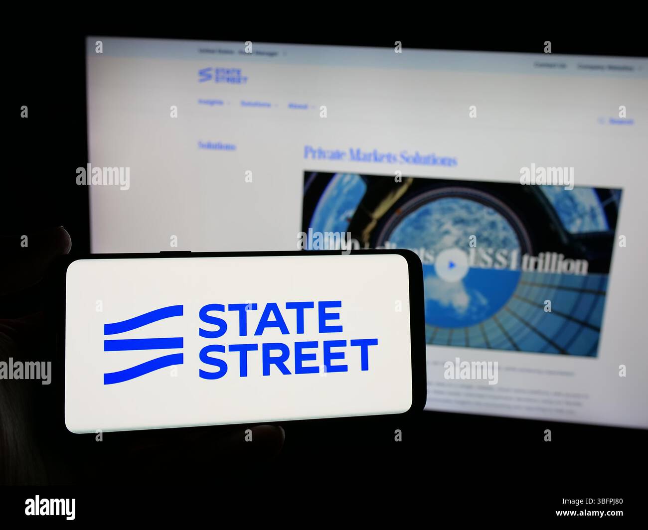 Stuttgart, Allemagne - 01-23-2025 : personne tenant un smartphone avec le logo de la société financière américaine State Street Corporation sur l'écran en face du site Web. Banque D'Images Stuttgart, Allemagne - 01-23-2025 : personne tenant un smartphone avec le logo de la société financière américaine State Street Corporation sur l'écran en face du site Web. Banque D'Images