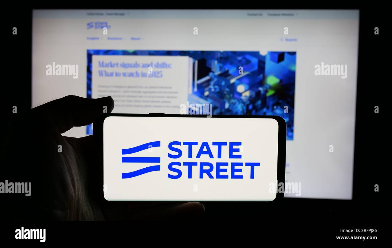Stuttgart, Allemagne - 01-23-2025 : personne tenant un téléphone portable avec le logo de la société financière américaine State Street Corporation sur l'écran Banque D'Images Stuttgart, Allemagne - 01-23-2025 : personne tenant un téléphone portable avec le logo de la société financière américaine State Street Corporation sur l'écran Banque D'Images
