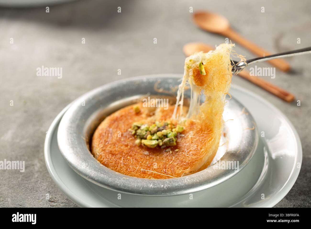 Kunafa à la crème et au fromage, garni de sirop de sucre et de pistaches écrasées, dessert arabe traditionnel Banque D'Images