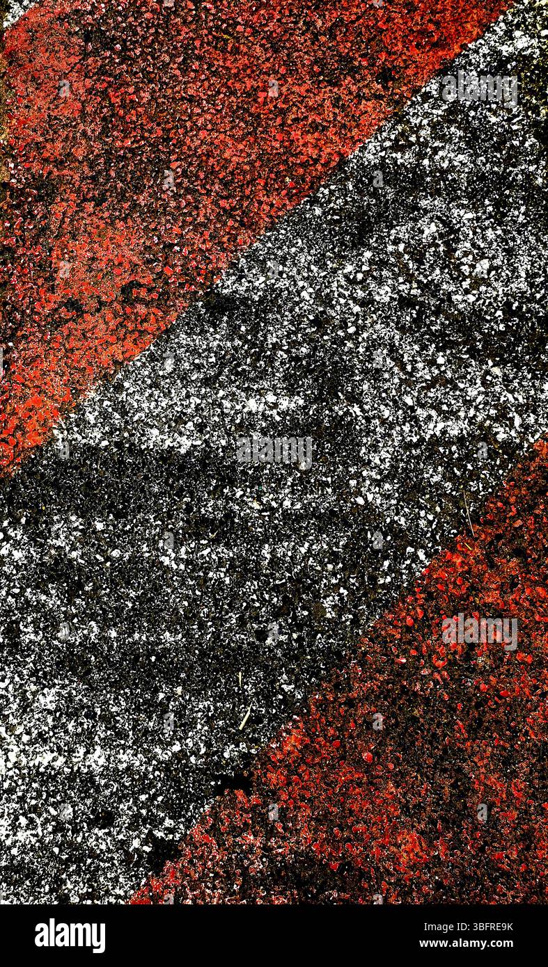 Vue rapprochée d'une chaussée texturée avec des rayures diagonales audacieuses en rouge et noir, mettant en valeur les surfaces usées et les couleurs contrastées sous midi - Image de stock capturée avec un smartphone