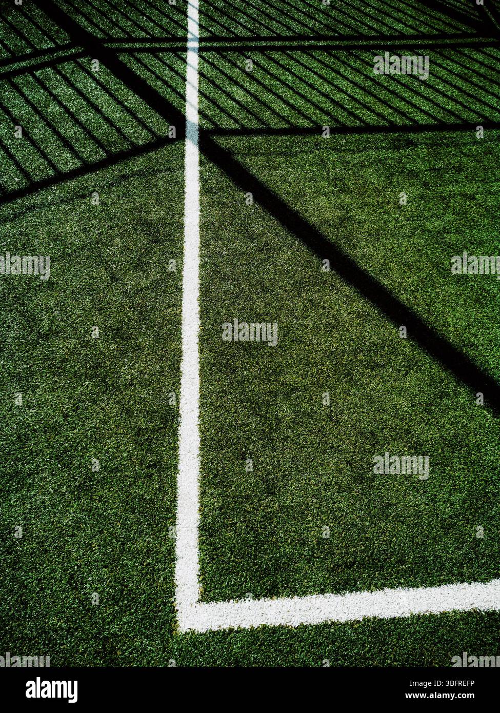 Ce coin d'un terrain de sport présente un gazon artificiel éclatant avec des lignes blanches claires marquant la limite. Banque D'Images