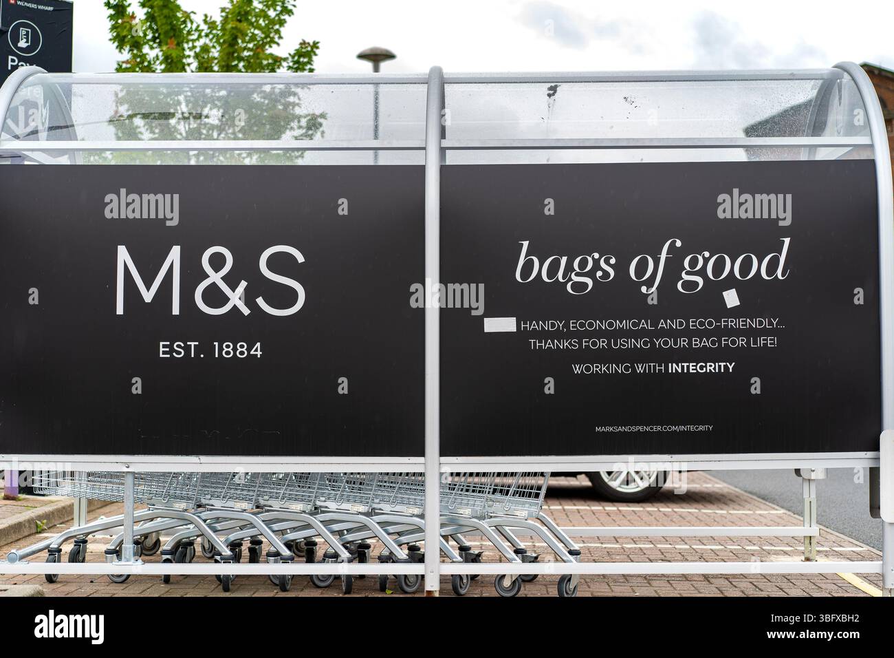 Chariot de magasinage abritant à l'extérieur d'un magasin britannique Marks and Spencer avec un panneau annonçant leurs sacs économiques et écologiques pour la vie comme des « sacs de bien ». Banque D'Images