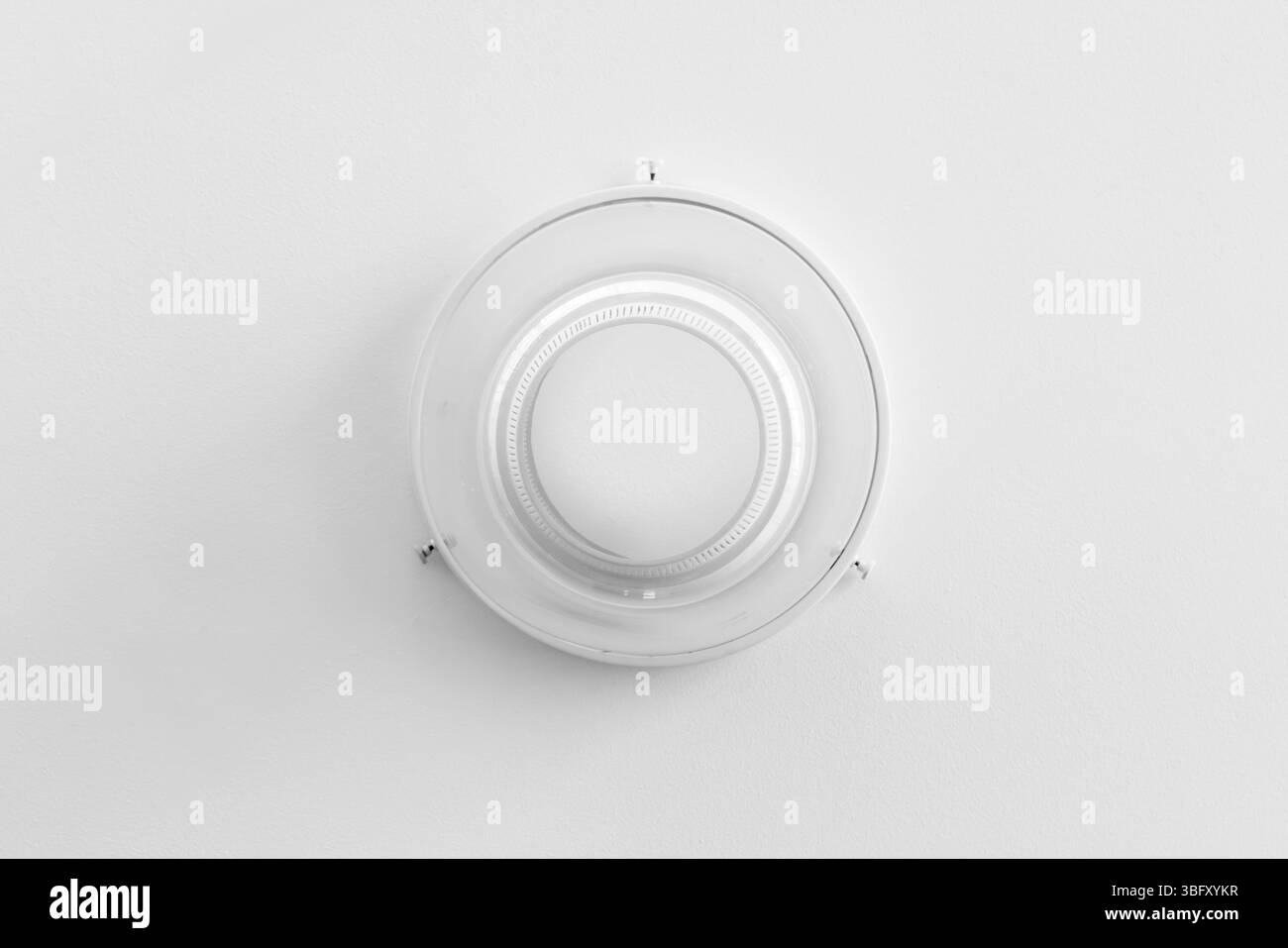 Une vue de haut en bas d'un plafonnier circulaire sur une surface blanche unie, soulignant la simplicité et la symétrie dans un thème monochrome Banque D'Images