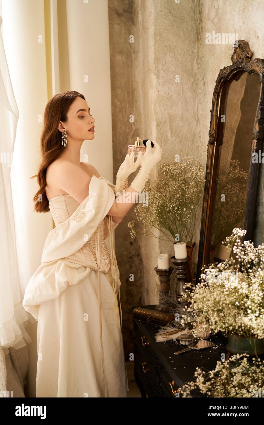 Une femme gracieuse dans une robe vintage se reflète par un miroir orné de fleurs. Banque D'Images
