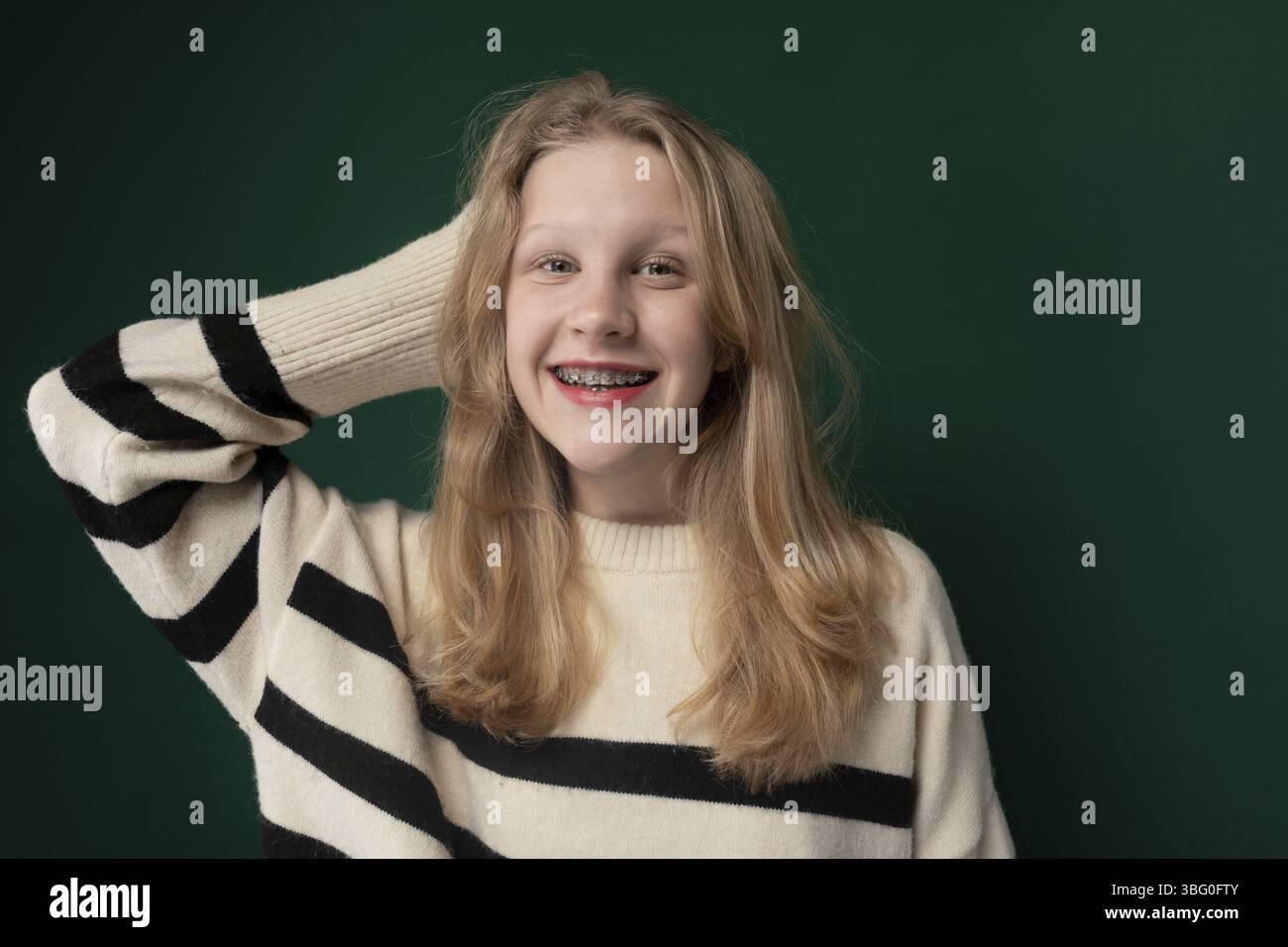 Une femme aux cheveux blonds est debout, portant un pull rayé. Elle semble calme et regarde vers l'avant. Sa tenue se compose d'un pull rayé qui Banque D'Images