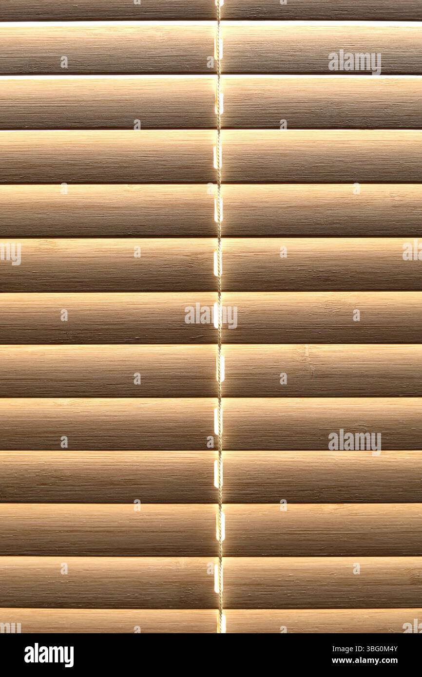Gros plan de la texture des stores de fenêtre en bambou fermés avec la lumière brillante par derrière. Vue de face Banque D'Images