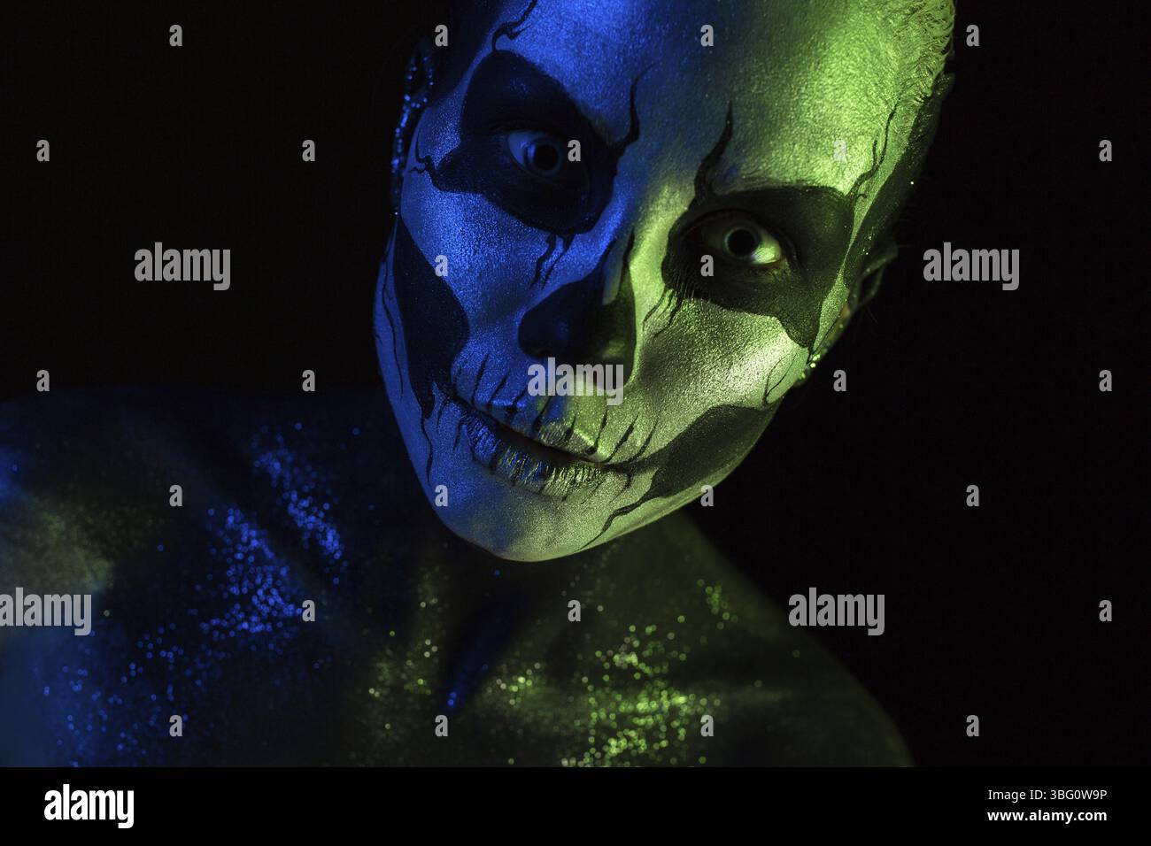 Isolé sur noir, gros plan photo, vert tonique et bleu, belle jeune femme caucasienne blonde effrayante avec l'art du corps de scull, les yeux gris, regard languissant, Banque D'Images