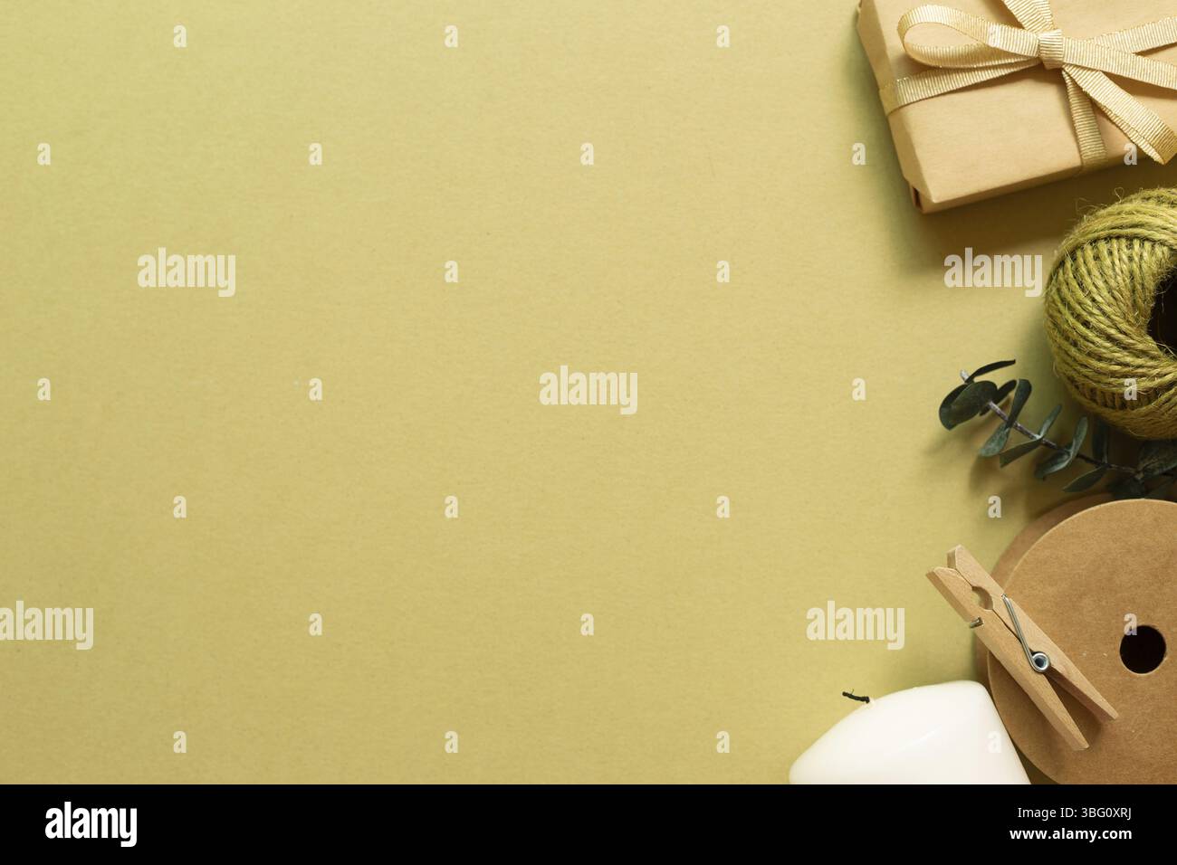 Boîte cadeau marron, rouleau de ficelle, bougie sur fond vert kaki. pose à plat, vue du dessus, espace pour copier Banque D'Images