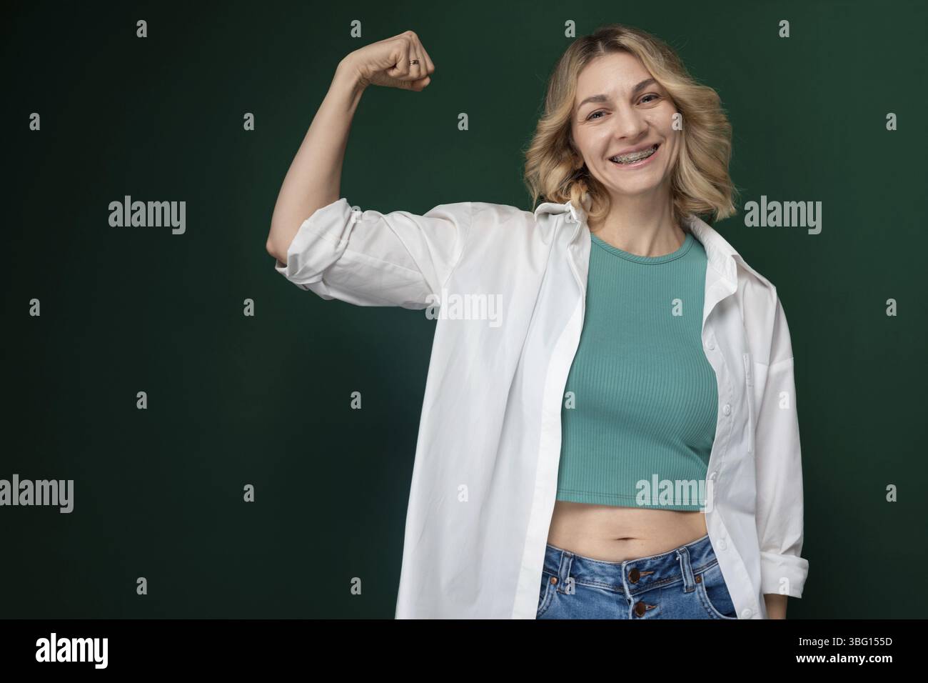 Une femme debout avec confiance avec son poing levé dans une pose pour une photo. Elle semble forte et déterminée, mettant en valeur l’autonomisation et la résilience Banque D'Images