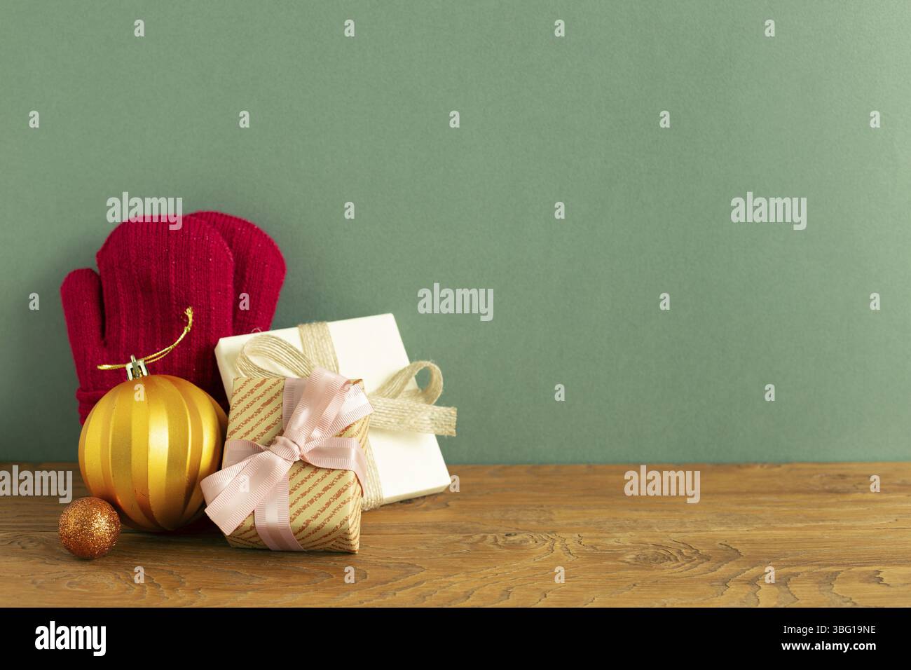 Concept de noël d'hiver.Gants d'hiver, boule, boîte cadeau sur table en bois. Fond vert. Espace de copie Banque D'Images