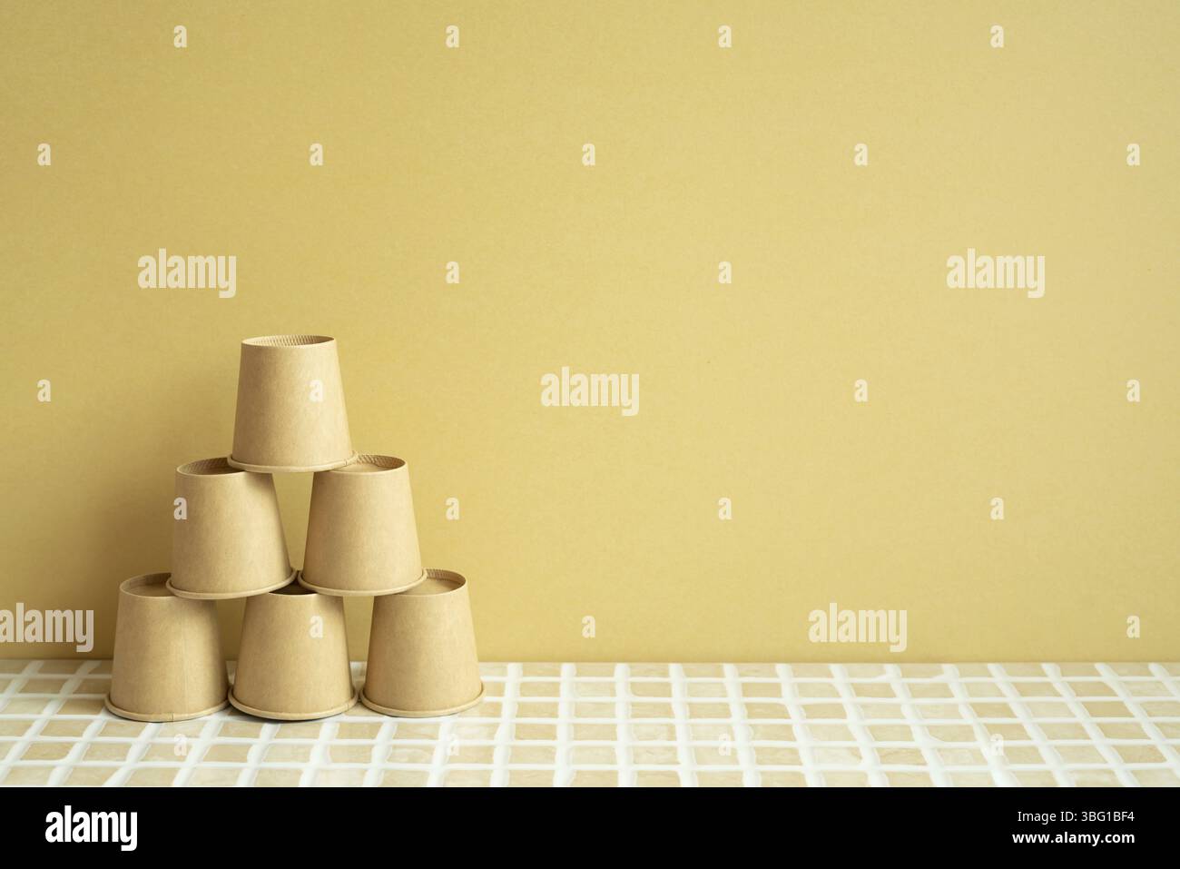 Pile pyramidale de gobelets bruns sur le bureau. arrière-plan jaune. développement de l'entreprise concept de croissance de la réalisation Banque D'Images