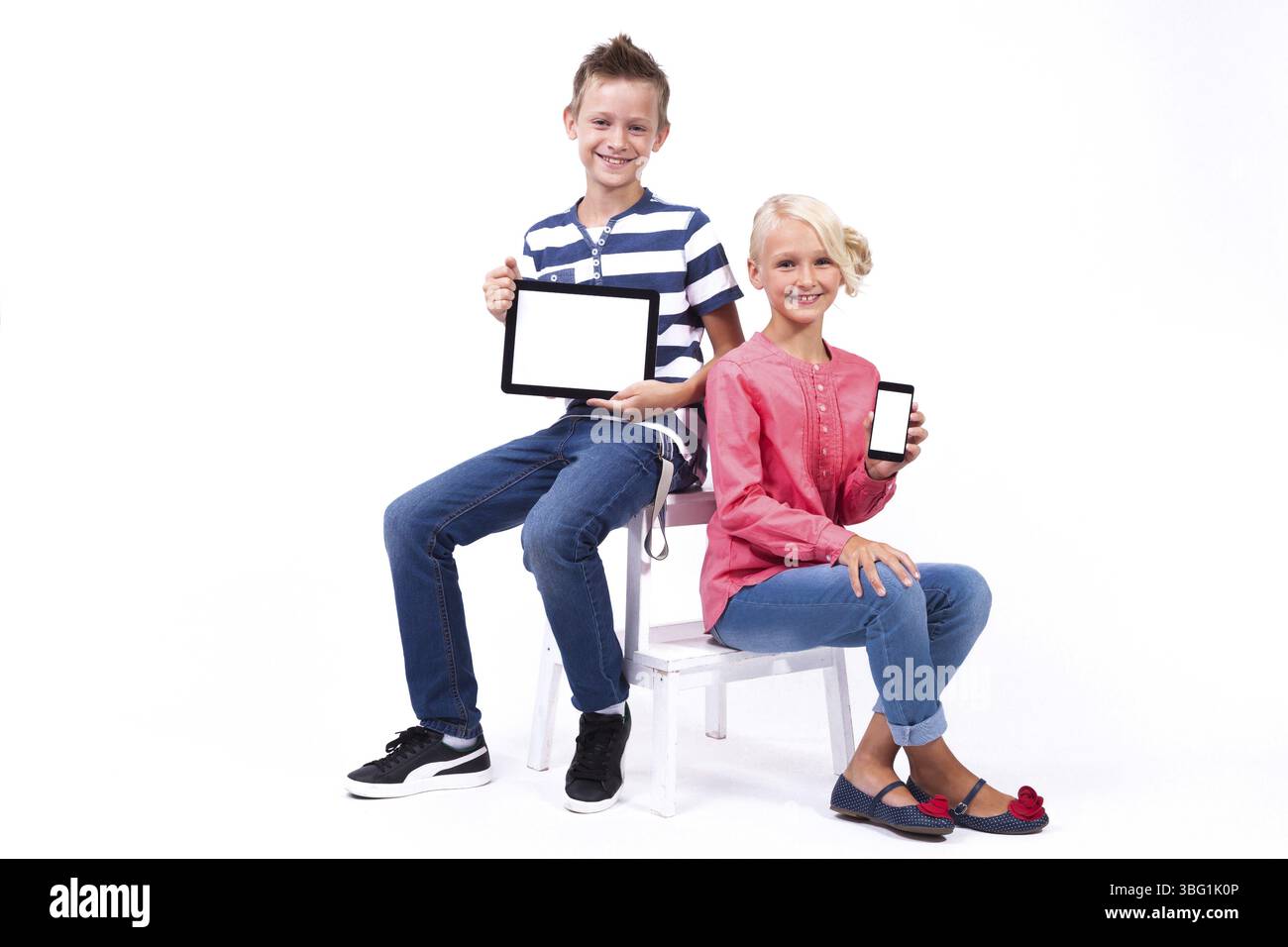 Les écoliers souriants apprennent à connaître le monde et communiquent à l'aide de tablettes et de téléphones modernes, une formation intéressante et la communication gad Banque D'Images
