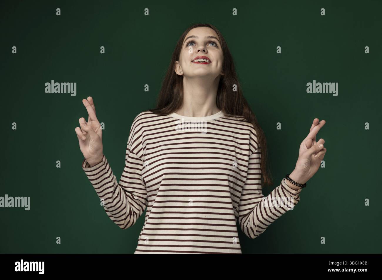 Une femme se tient devant un mur vert éclatant. Elle semble contemplative en regardant au loin. Le contraste entre sa silhouette et le Banque D'Images