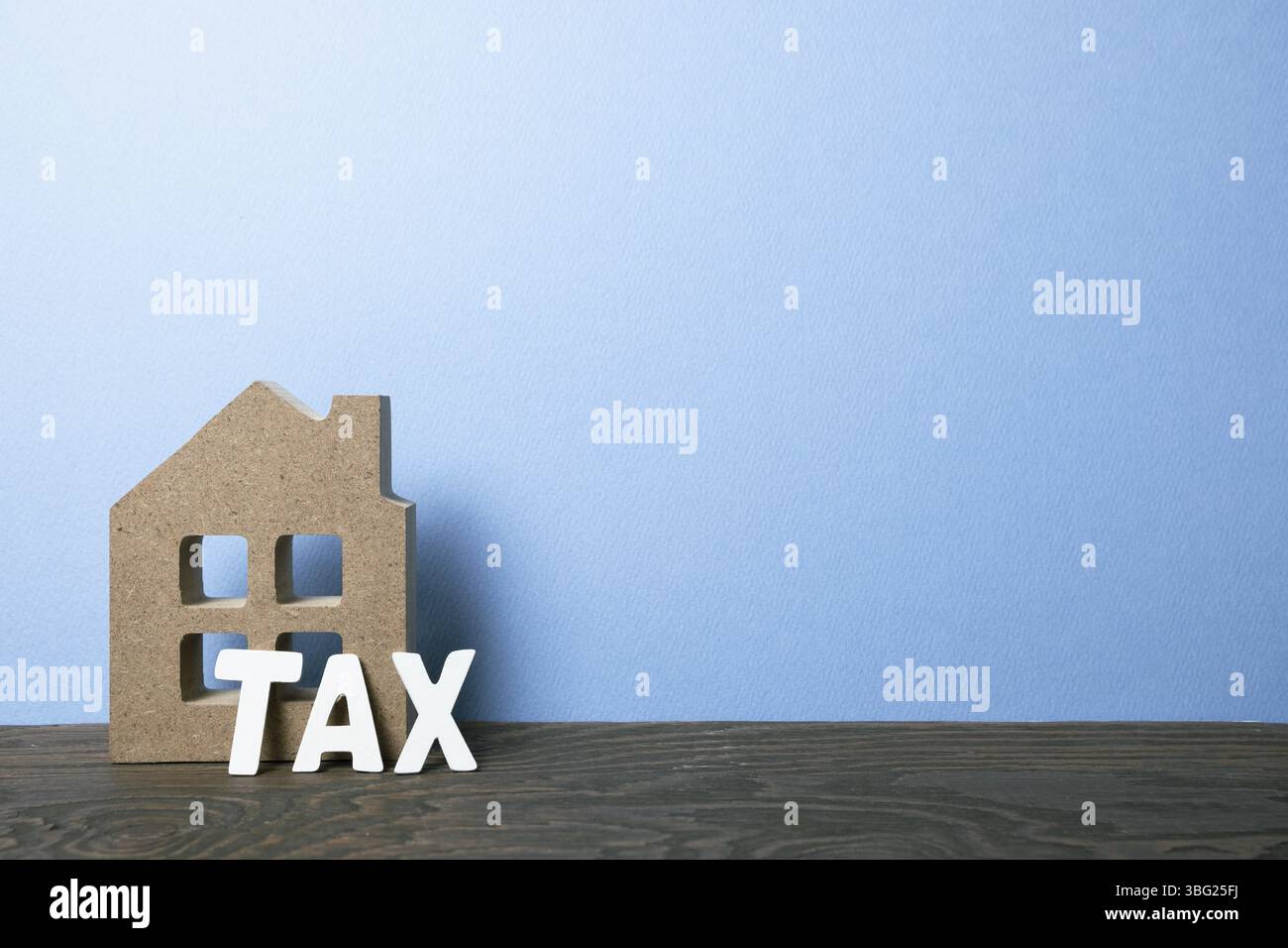 Modèle maison avec taxe sur table en bois avec fond bleu. Concept d'hypothèque ou d'impôt foncier Banque D'Images
