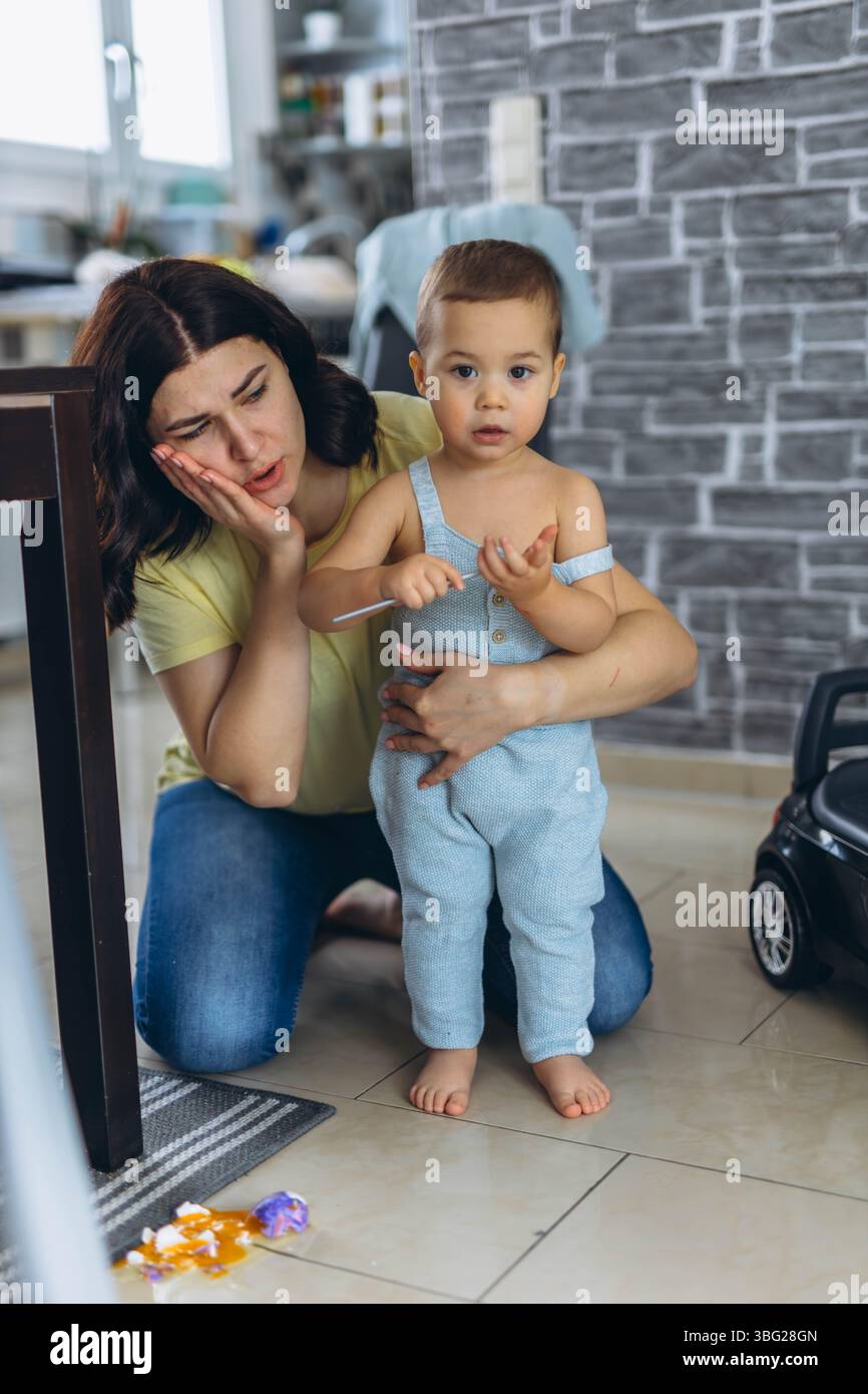 Mère en colère grongeant son fils pour avoir cassé un œuf dans la cuisine. Parentalité et concept de discipline. Photo de haute qualité Banque D'Images
