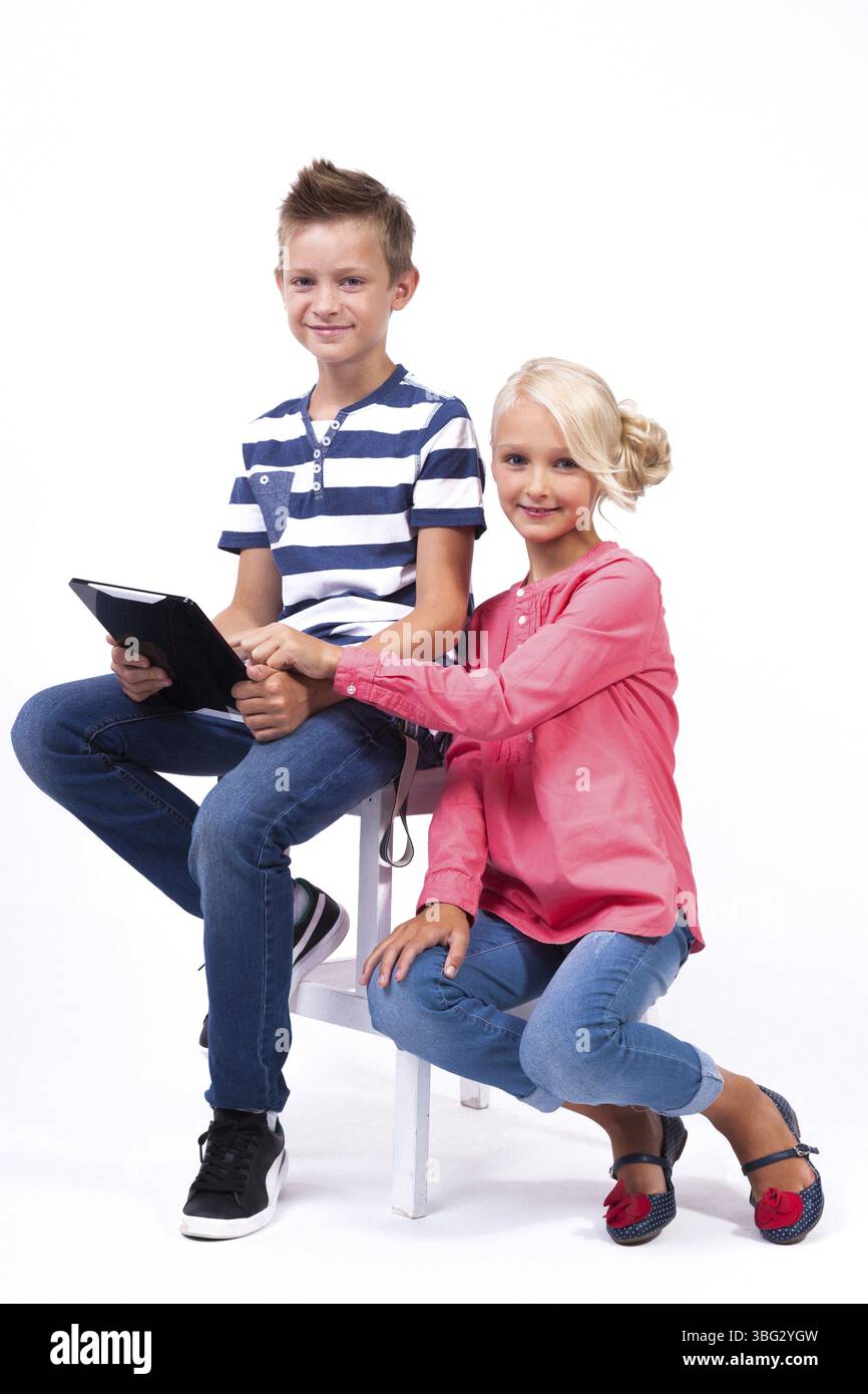 Les écoliers souriants apprennent à connaître le monde et communiquent à l'aide de tablettes et de téléphones modernes, une formation intéressante et la communication gad Banque D'Images