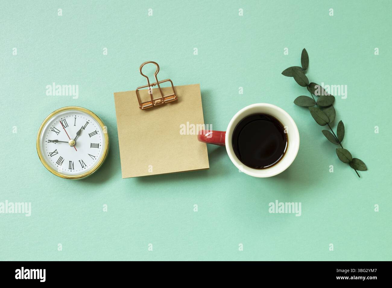 Bloc-notes, horloge, tasse de café, feuille verte sur fond vert menthe. bureau, espace de travail. Vue du dessus Banque D'Images