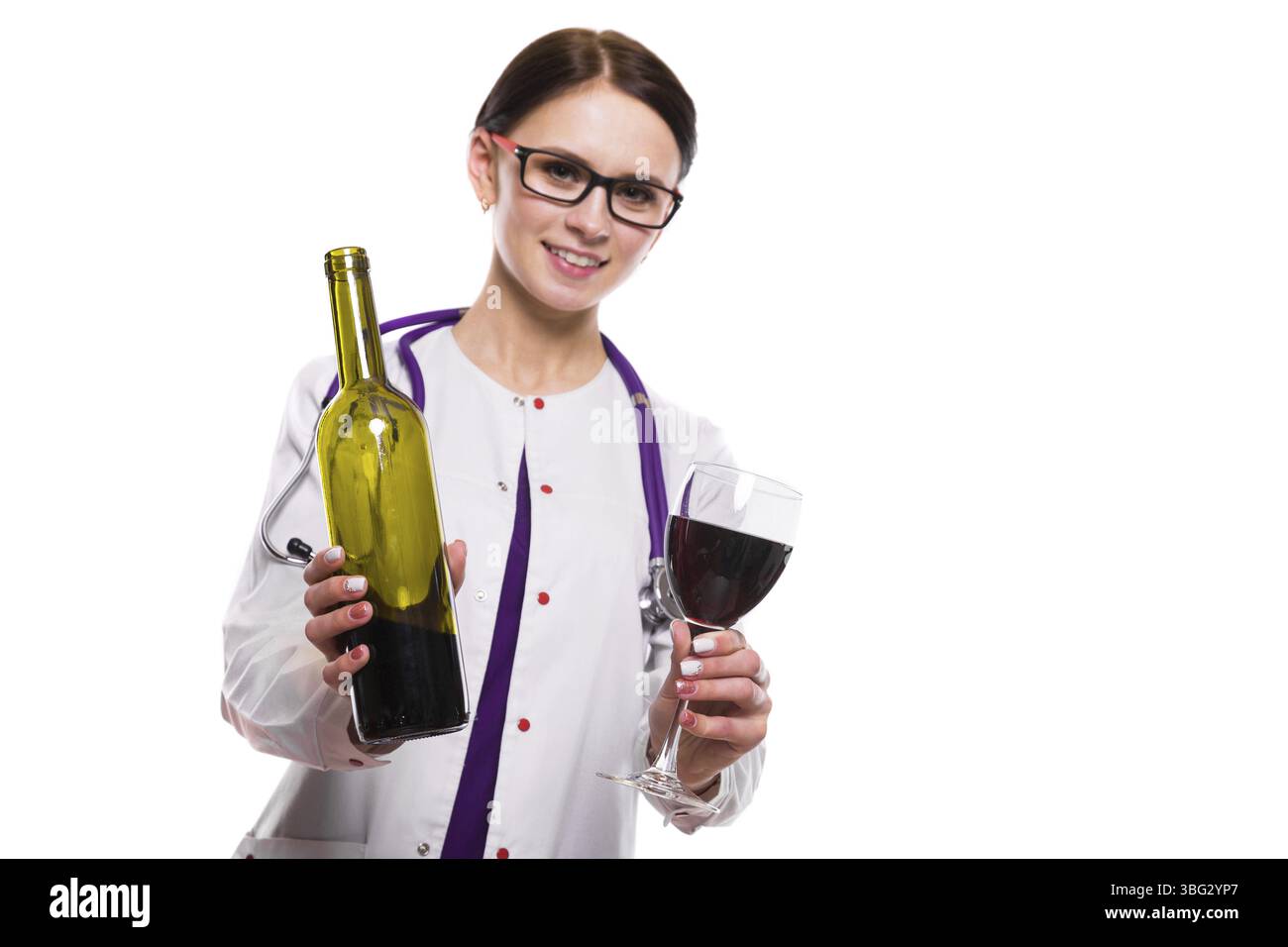 Portrait de jeune femme médecin attrayant en manteau blanc souriant regardant dans la caméra tenant bouteille et verre de vin Banque D'Images