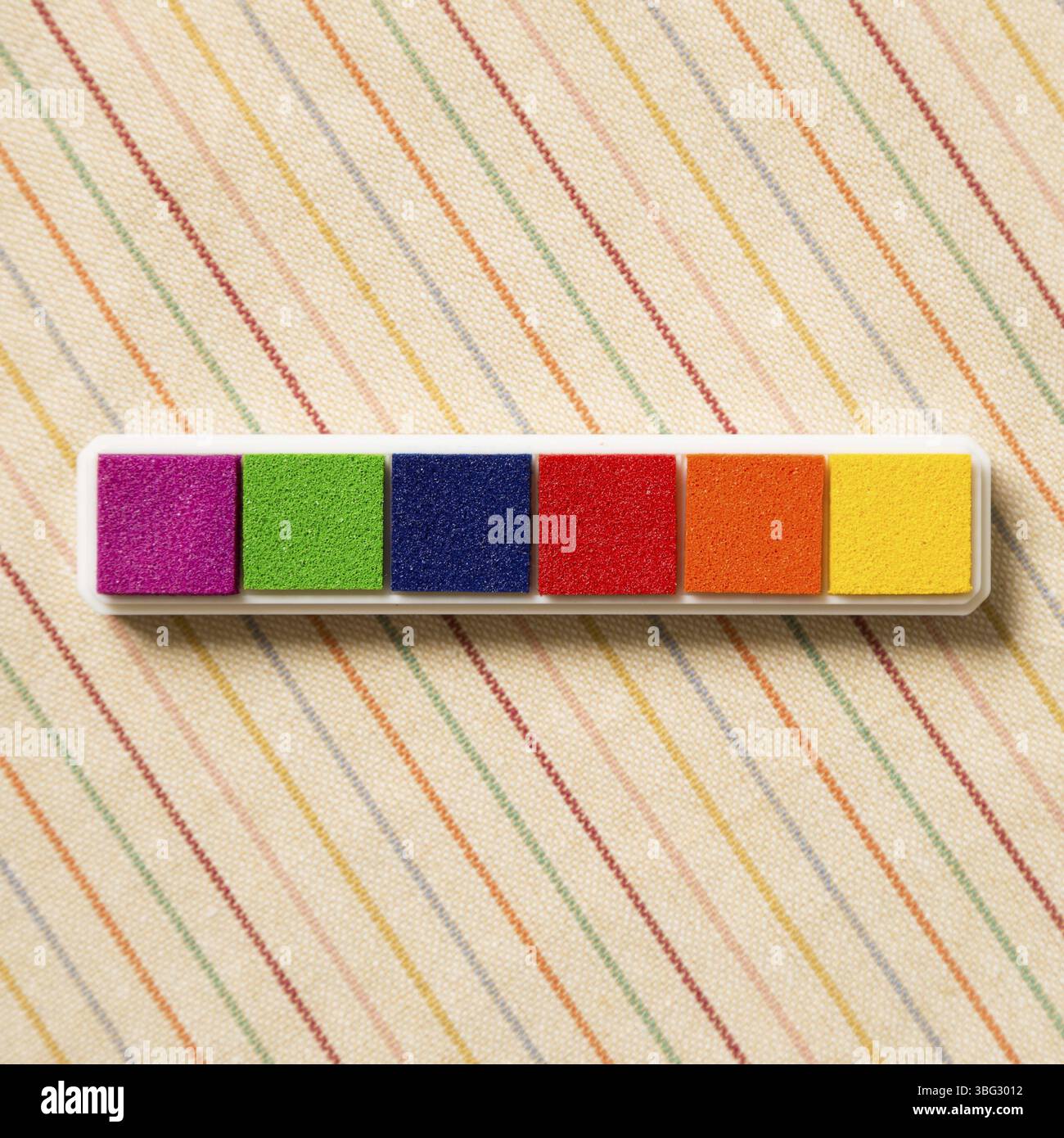 Tampon encreur timbre coloré motif hachuré sur fond de tissu Banque D'Images