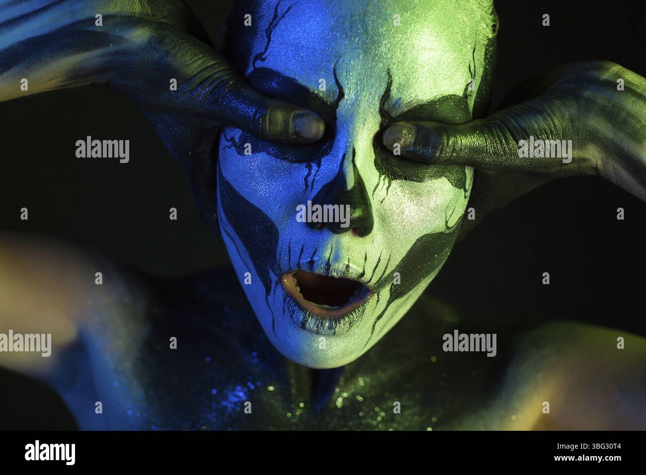 Isolé sur noir, photo en gros plan, vert et bleu tonifié, jeune femme caucasienne blonde effrayante avec de l'art du corps scull, les yeux gris fermés, la ferme Banque D'Images
