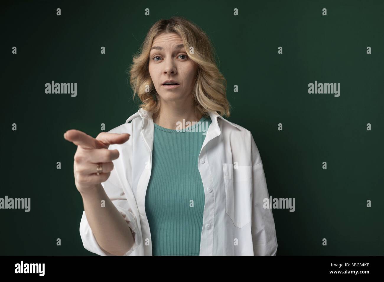 Une femme portant une veste blanche pointe vers un objet ou une direction non spécifié. Son geste indique qu'elle attire l'attention sur un particulier Banque D'Images