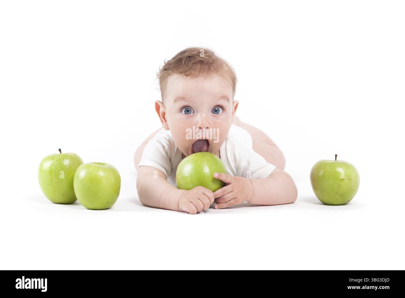 Isolé sur blanc, bébé garçon caucasien en chemise blanche se trouve avec des pommes vertes, bouche ouverte Banque D'Images