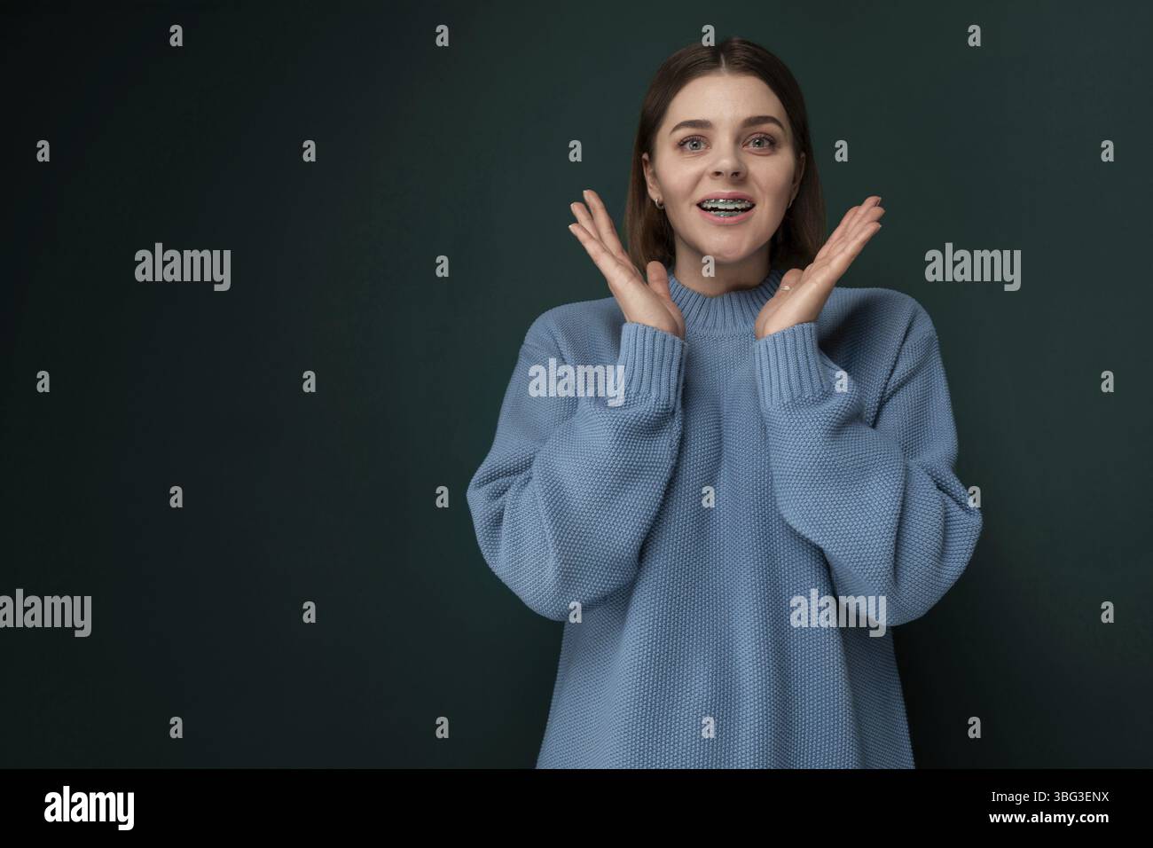 Une femme portant un pull bleu se tient debout, les mains levées en l'air. Elle semble déterminée et confiante dans sa posture Banque D'Images