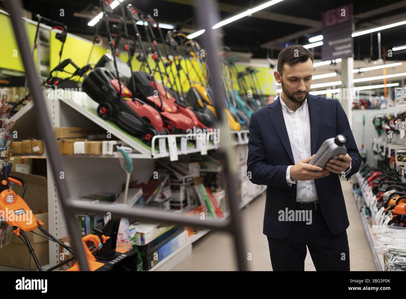 Un client d'un magasin choisit de l'huile moteur pour une tondeuse à essence Banque D'Images