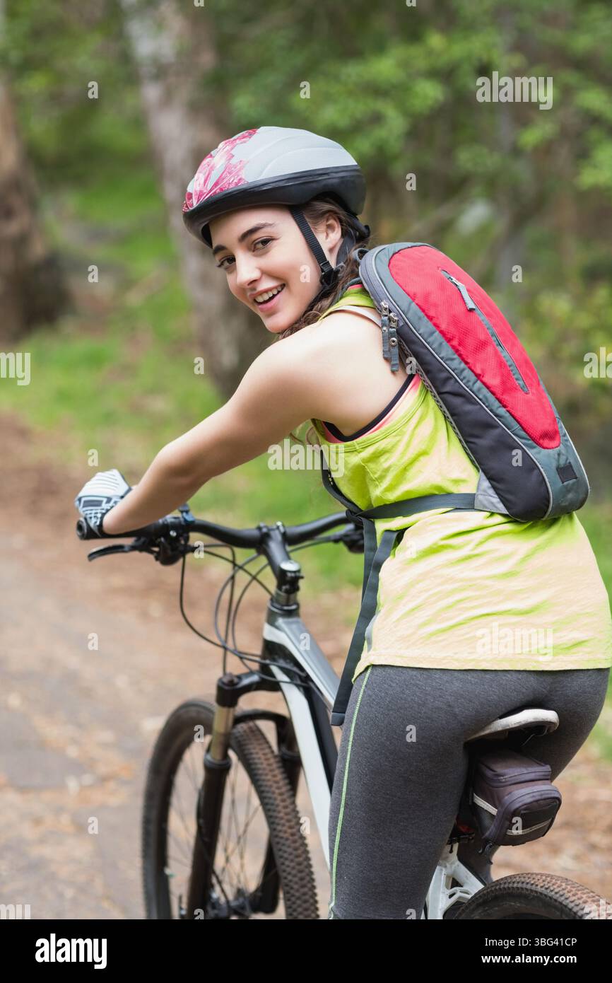 Cycliste faisant du VTT le long d'un sentier boisé en terre battue, portant un équipement néon et un pack d'hydratation Banque D'Images Cycliste faisant du VTT le long d'un sentier boisé en terre battue, portant un équipement néon et un pack d'hydratation Banque D'Images