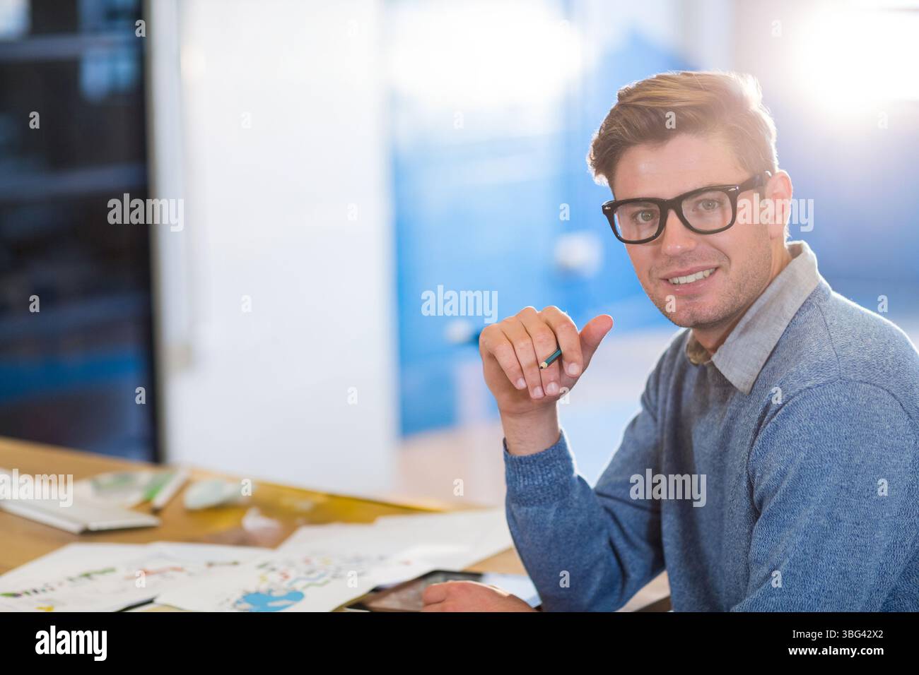 Homme assis esquissant sur une table de travail en bois dans un studio de design avec des papiers au crayon et à croquis, espace de copie Banque D'Images