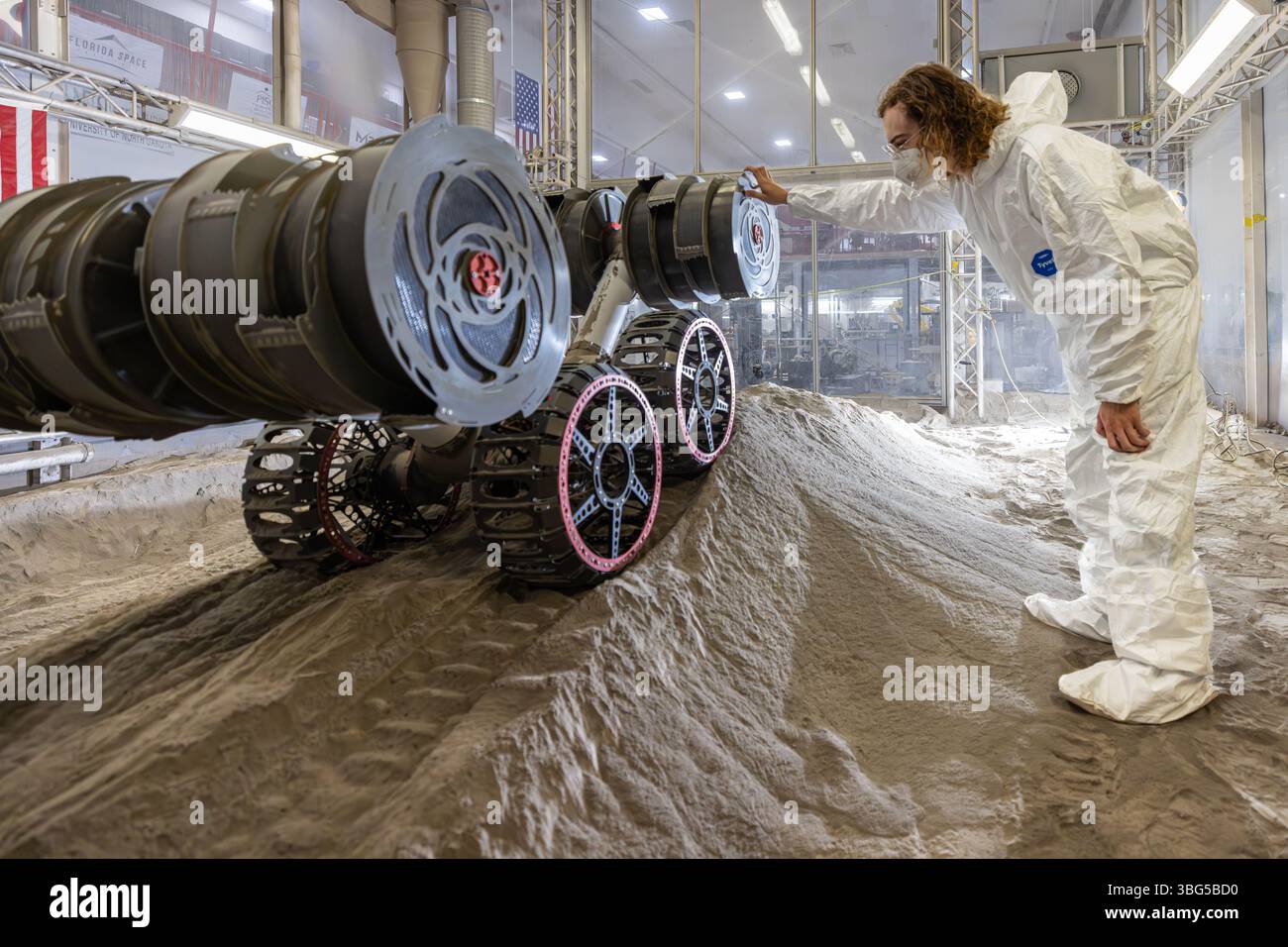 Un ingénieur de la NASA observe un robot lunaire RASSOR lors d'un essai d'excavation au Kennedy Space Center, en Floride, en mai 2025 Banque D'Images