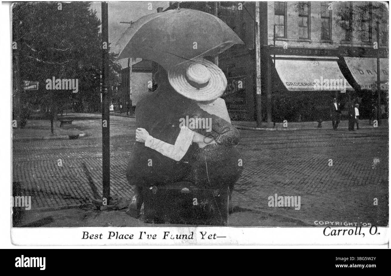 Cette image montre une scène de nouveauté de Carroll, Ohio, avec un homme et une femme assis sous un parapluie, contemplant le centre-ville. Le cadre paisible met en valeur le paysage local et l'atmosphère communautaire de la ville. Banque D'Images