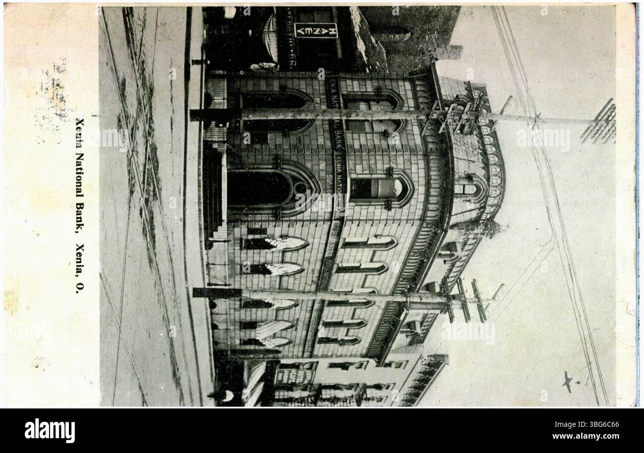 Une photographie en noir et blanc de la Xenia National Bank de Xenia, Ohio, en 1911. L'image montre le bâtiment de la banque avec des lignes de tramway visibles dans la rue, offrant un aperçu de la vie urbaine du début du XXe siècle. Banque D'Images