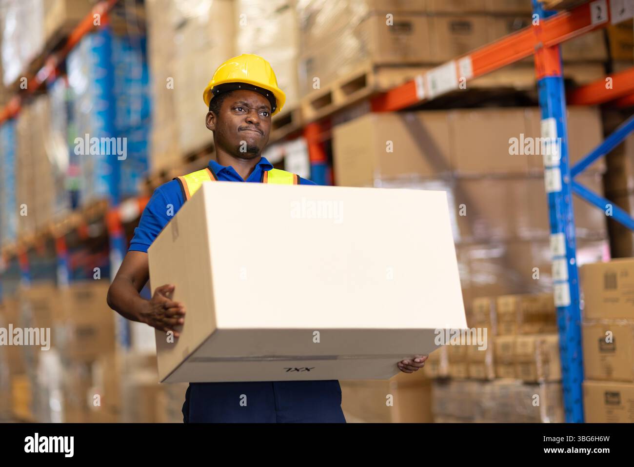 travailleur d'entrepôt transportant la boîte de levage de poids très lourd boîte de stockage mobile dans la douleur de dos de muscle de cargaison Banque D'Images