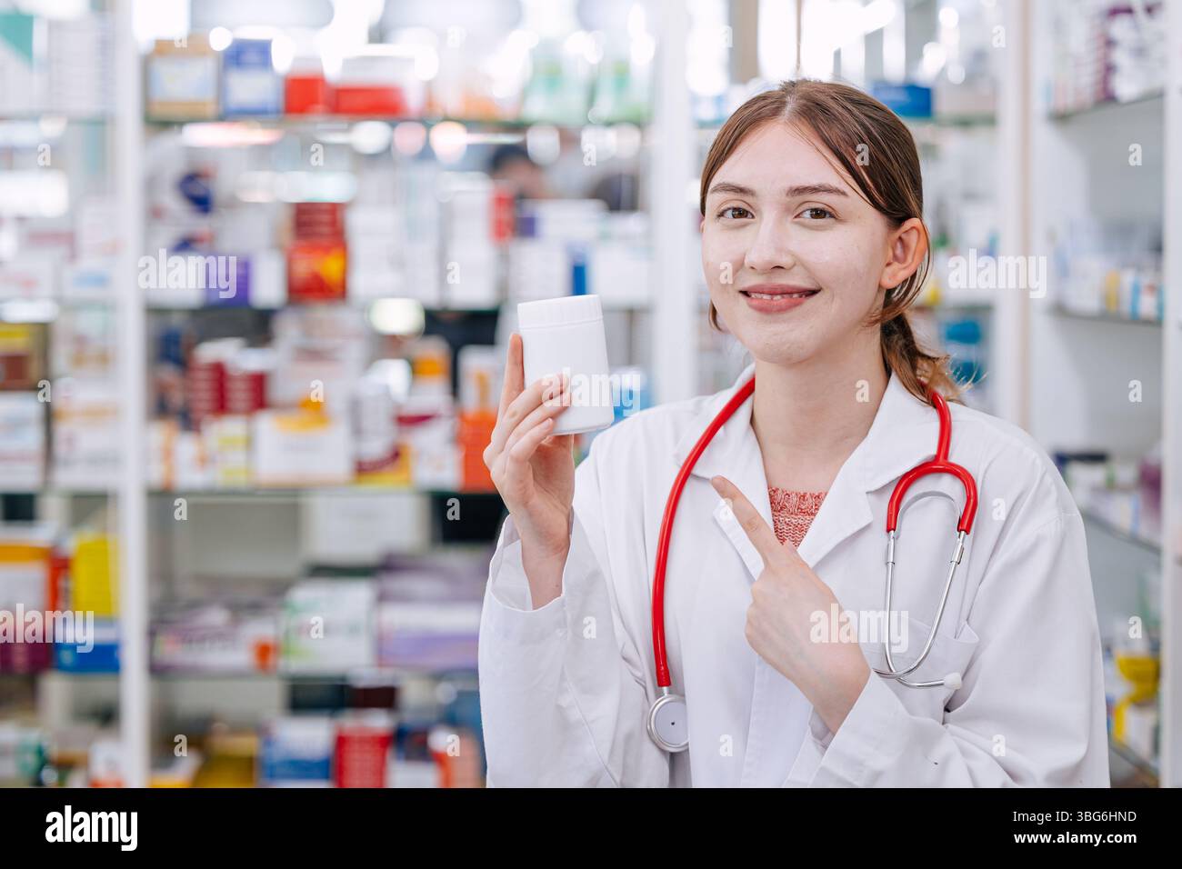 Heureux médecin pharmacien dans la main de magasin de drogue tenant pointant à la boîte de pilules de médecine pour recommander une bonne médecine souriante Banque D'Images