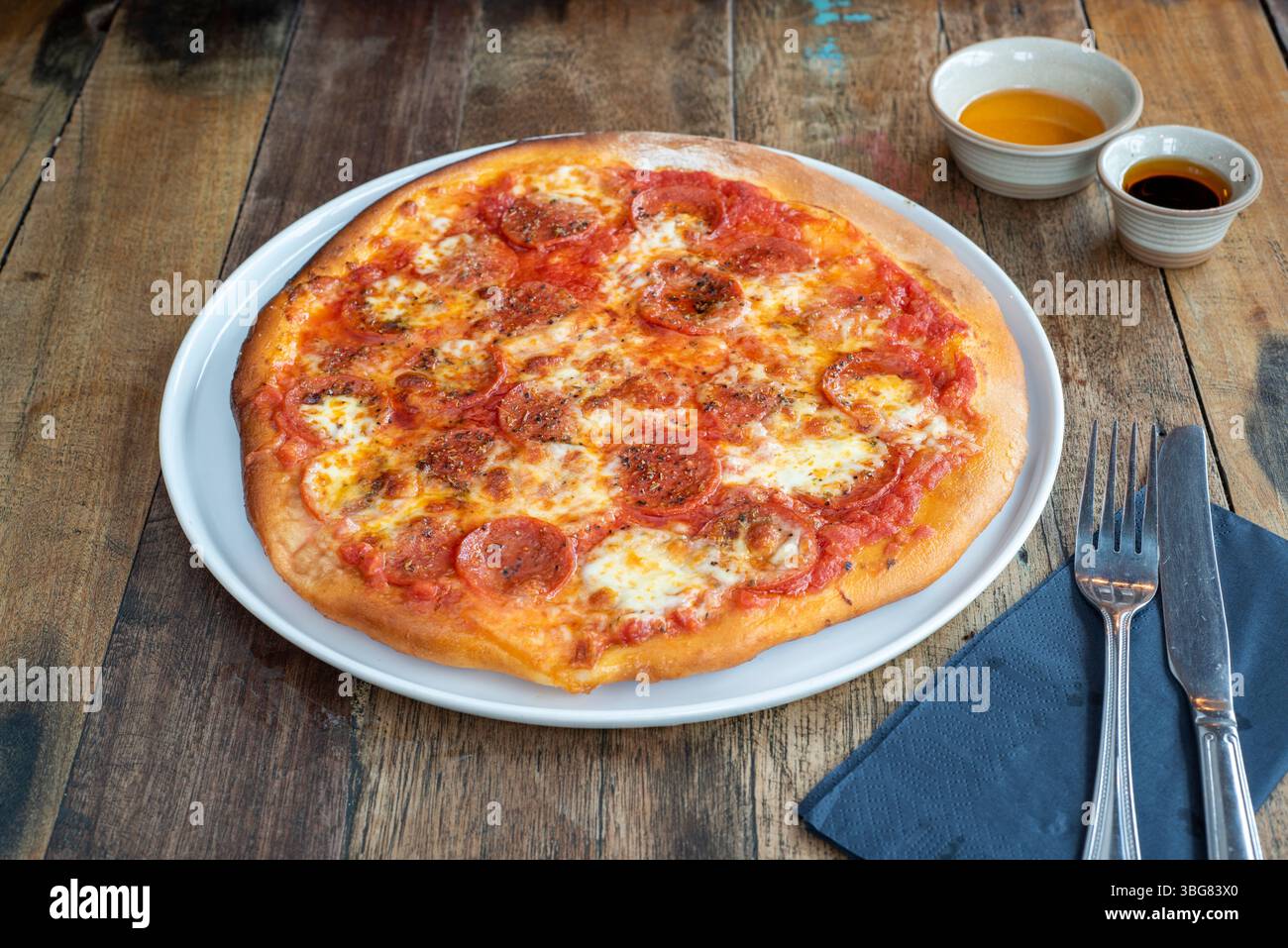 Pizza classique au pepperoni artisanale cuite au four avec sauce tomate, pepperoni au fromage et une pincée de poivre noir Banque D'Images