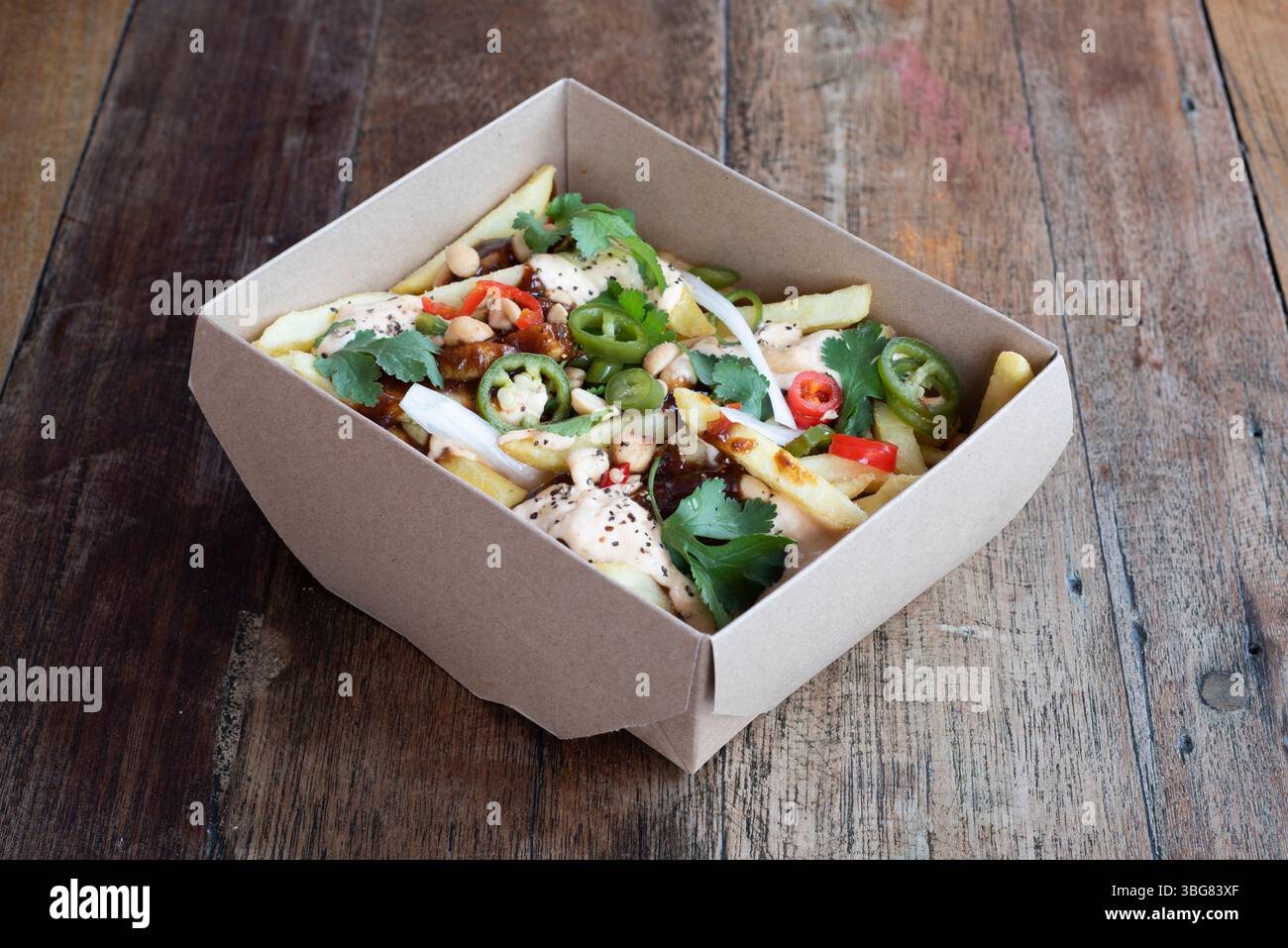 Frites vietnamiennes – frites de pommes de terre garnies de piments frais, de coriandre, d'arachides et d'une sauce secrète Banque D'Images
