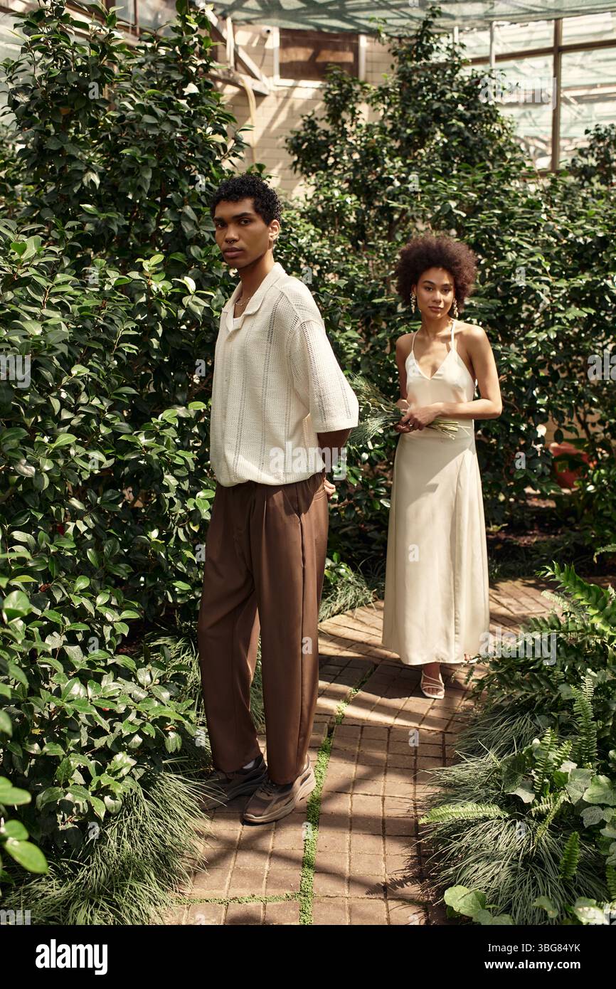 Un jeune couple profite d'une promenade romantique dans une belle serre entourée de plantes luxuriantes. Banque D'Images