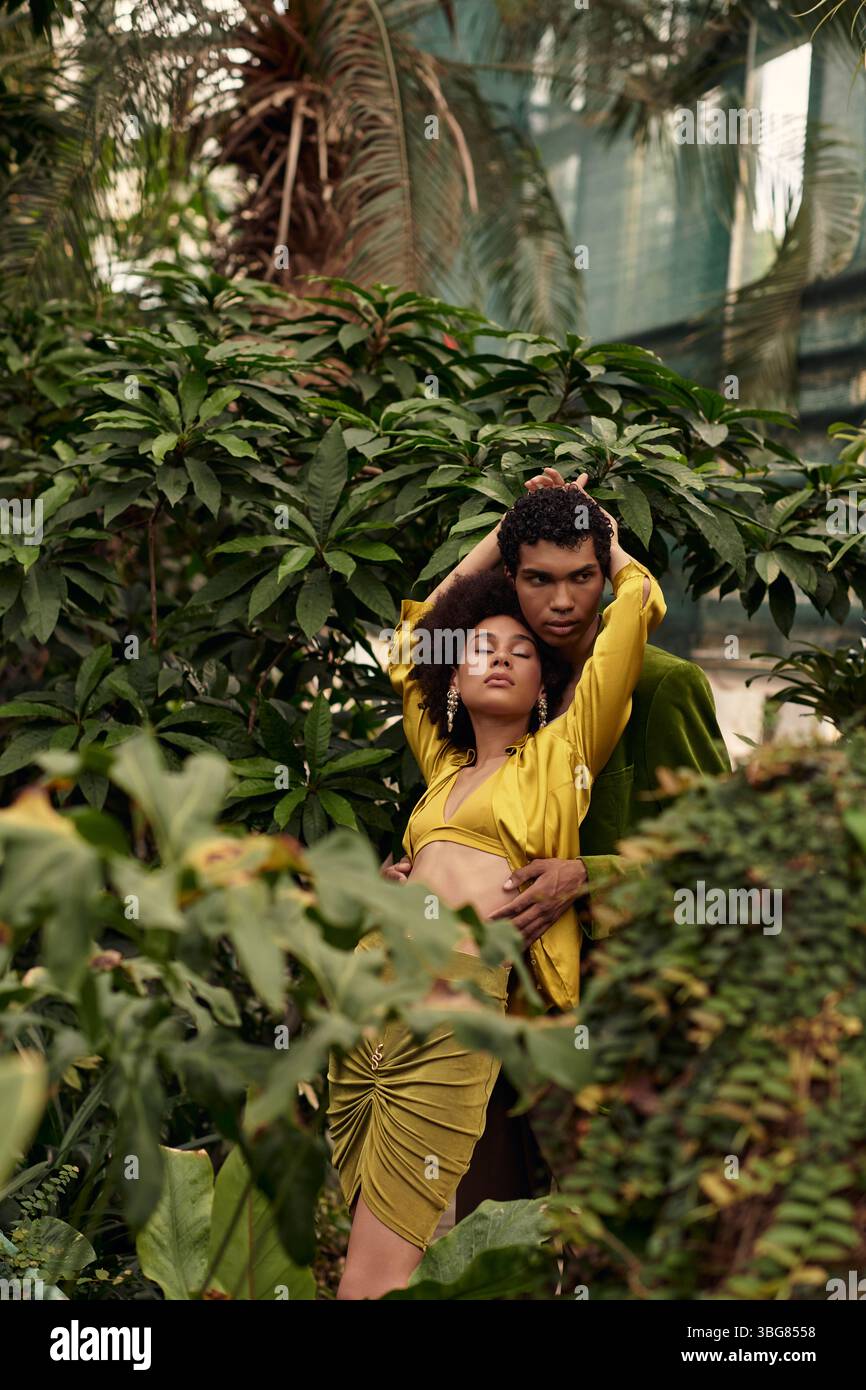 Dans une serre sereine, un couple aimant embrasse au milieu d'une riche tapisserie de plantes, rayonnant de joie. Banque D'Images