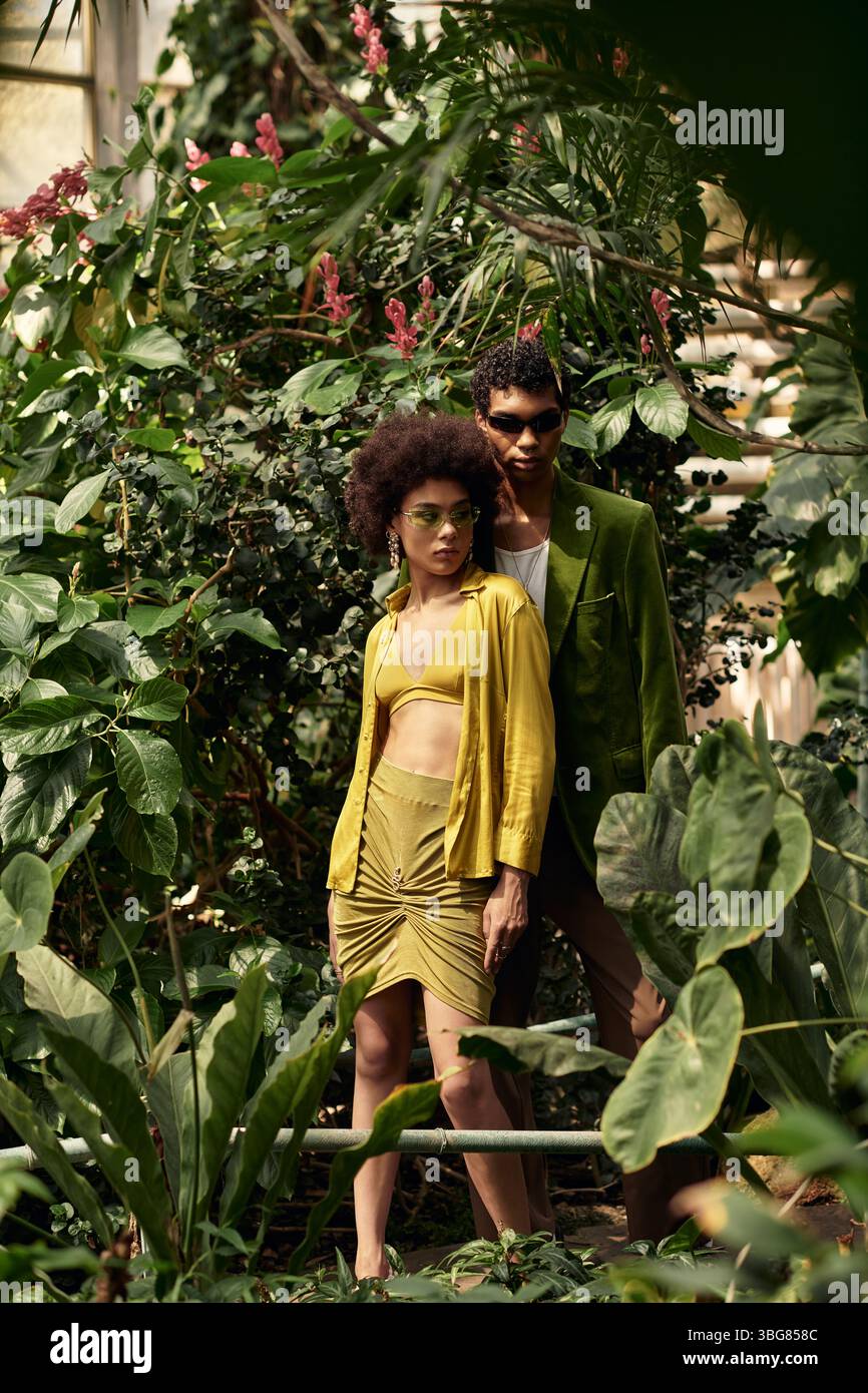 Dans une belle serre, un jeune couple embrasse tout en étant entouré de plantes riches et de verdure. Banque D'Images
