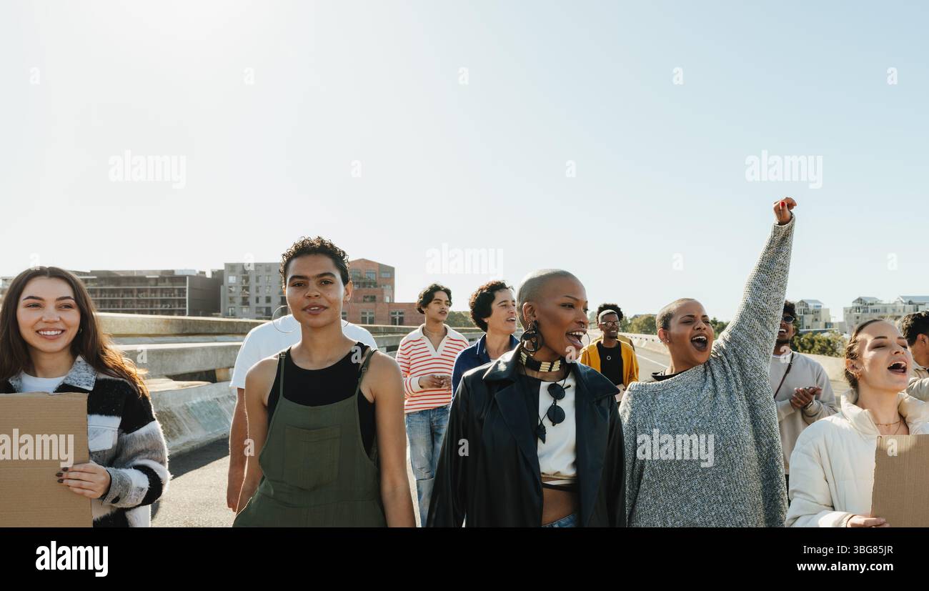 Un groupe de personnes dans une manifestation pacifique, exprimant leur solidarité et plaidant pour une cause. Les divers manifestants sont à l'extérieur sous un s bleu clair Banque D'Images