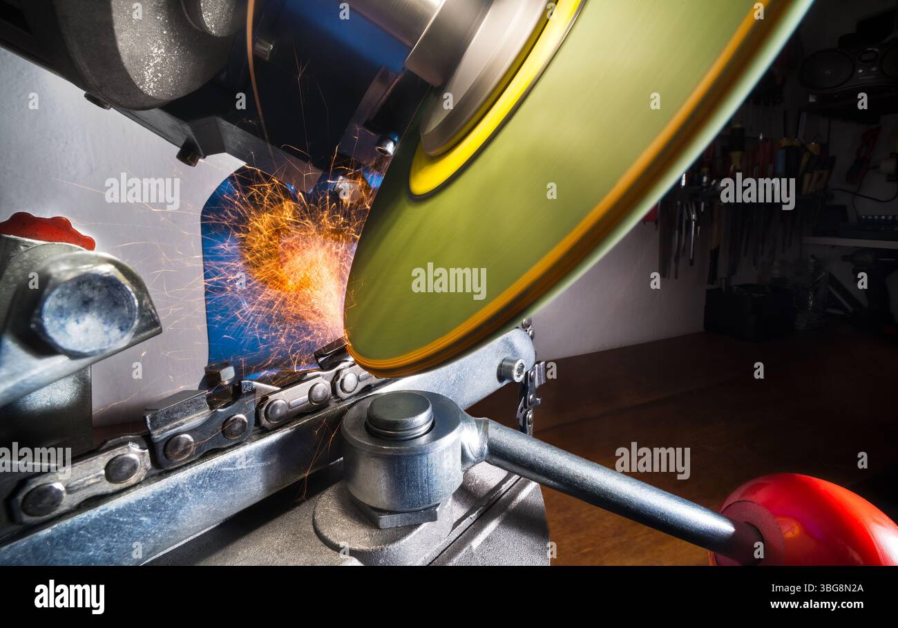 Affûtage de la chaîne de tronçonneuse par disque rotatif de rectifieuse. Lame tranchante de la roue et étincelles chaudes au niveau du bord de dent en acier de meulage de l'outil de coupe. Banque D'Images