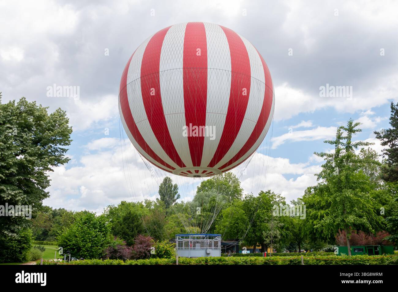 Un ballon captif rouge et blanc dans un parc parmi les arbres verts Banque D'Images