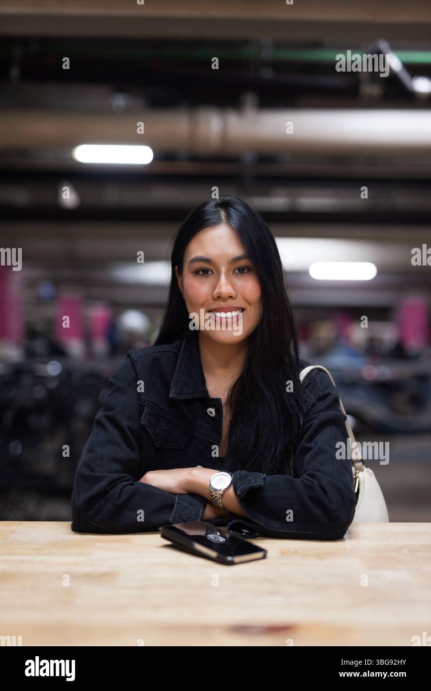 Portrait de jeune belle femme asiatique heureuse assise au parking pendant la nuit Banque D'Images