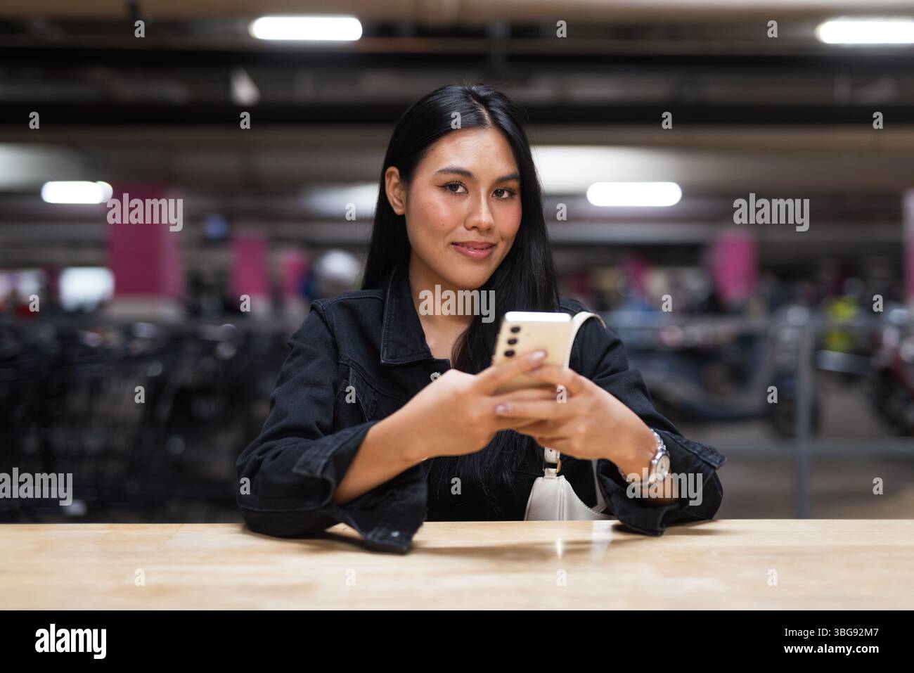 Portrait de jeune belle femme asiatique heureuse assise au parking pendant la nuit Banque D'Images
