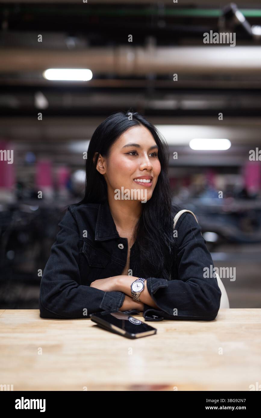 Portrait de jeune belle femme asiatique heureuse assise au parking pendant la nuit Banque D'Images