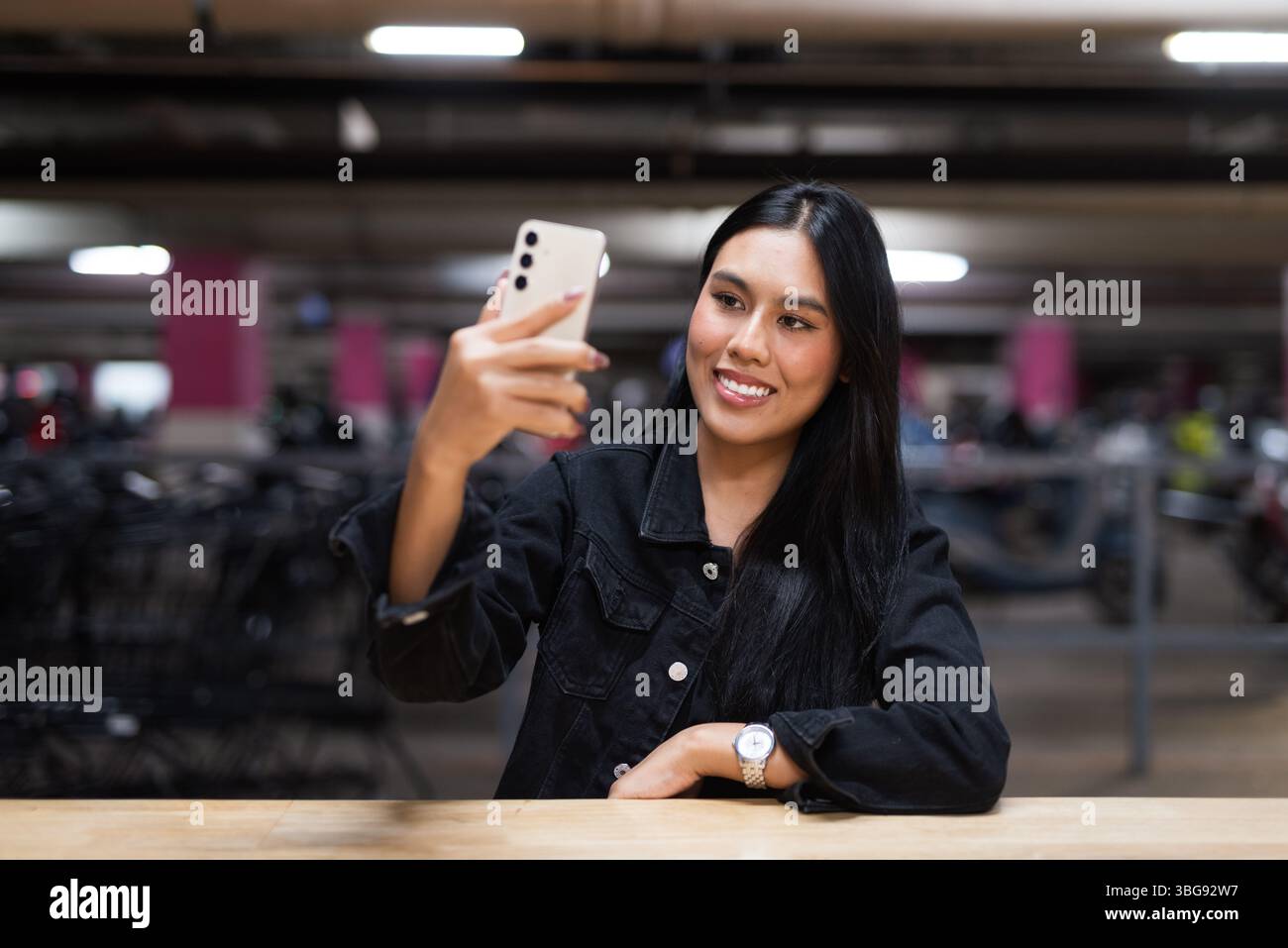 Portrait de jeune belle femme asiatique heureuse assise au parking pendant la nuit Banque D'Images